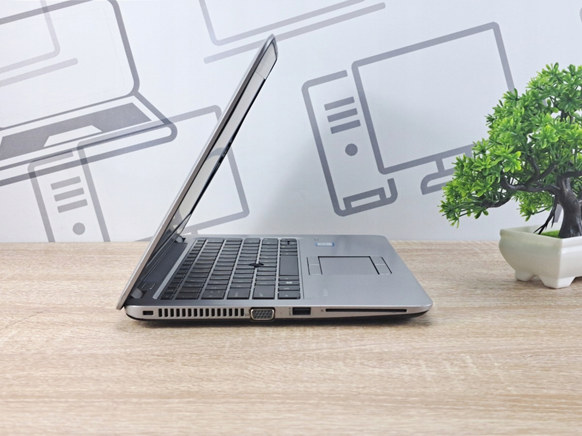 Laptop HP EliteBook 820 G3 uchylony pod kątem, widok z boku na zawias, klawiaturę i porty boczne.