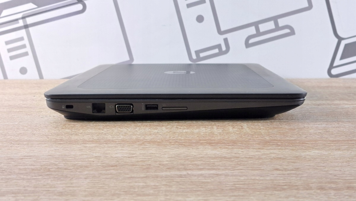 Zamknięty laptop HP ZBook widoczny z lewego boku, z portem blokady, VGA, USB i czytnikiem kart pamięci.