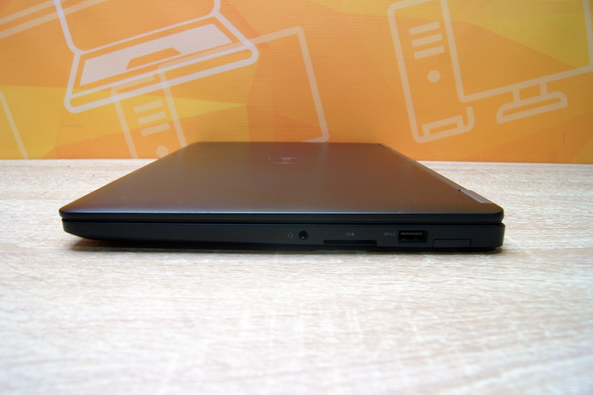 Zamknięty laptop Dell E7270 widziany z boku, widoczne złącze zasilania i port USB na krawędzi obudowy.
