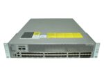 Przód switcha Cisco z wieloma rzędami portów SFP+, żółtą naklejką ostrzegawczą i uszami montażowymi po bokach.