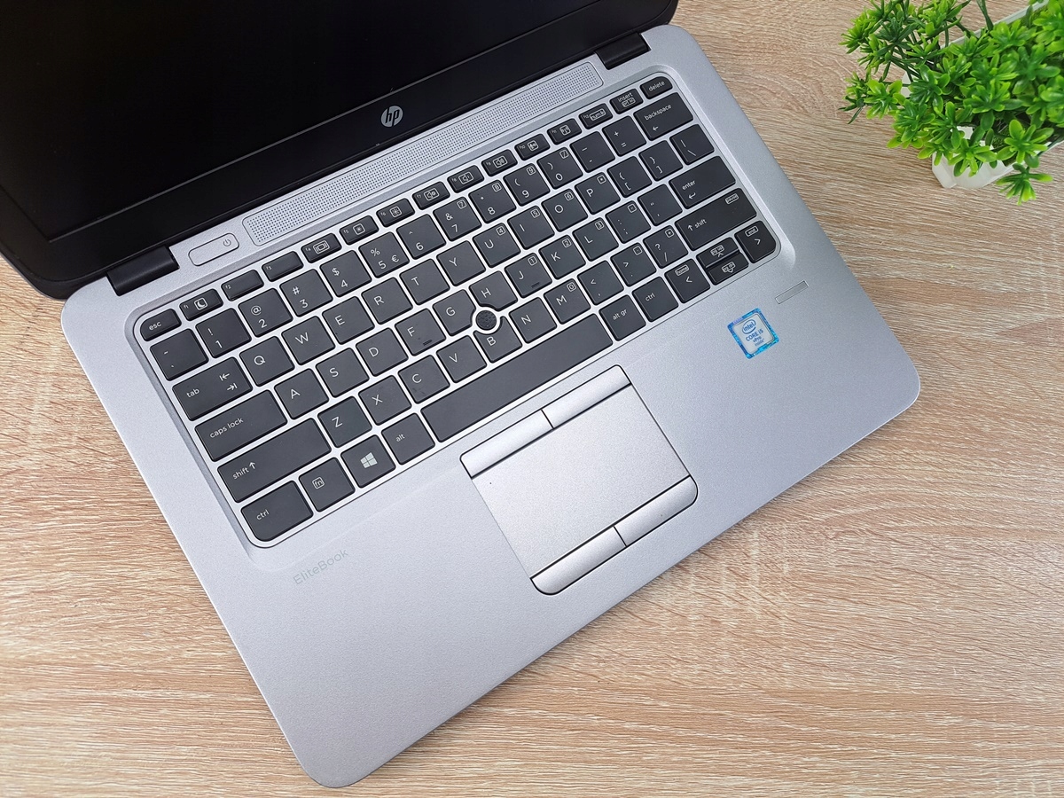 Otwarty laptop HP EliteBook widziany z góry, widoczna klawiatura, touchpad i zaokrąglone krawędzie obudowy z lekkimi przetarciami.