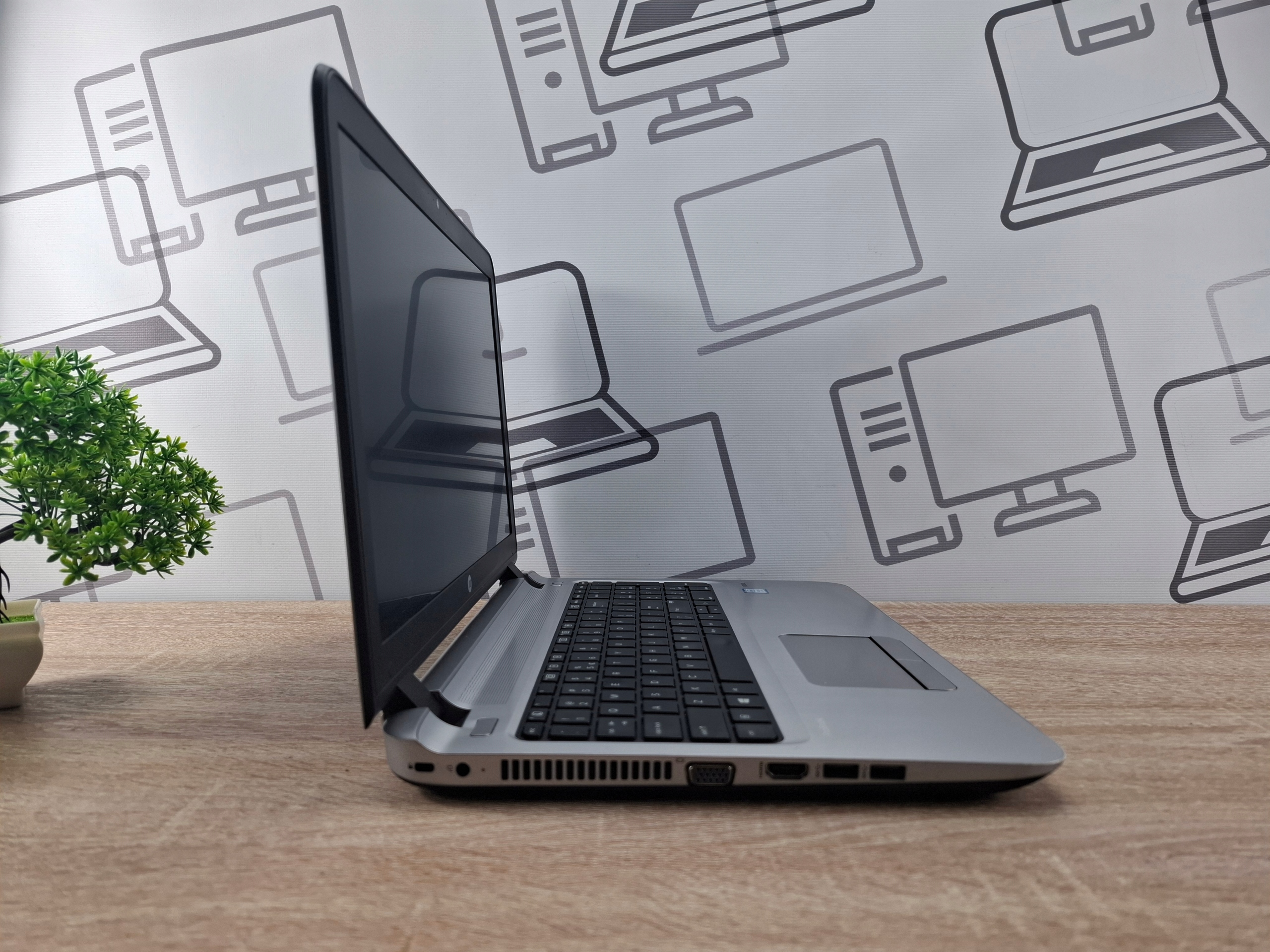Laptop HP ProBook 450 G3 uchylony bokiem, widoczna klawiatura, otwory wentylacyjne i porty z lewej strony obudowy.
