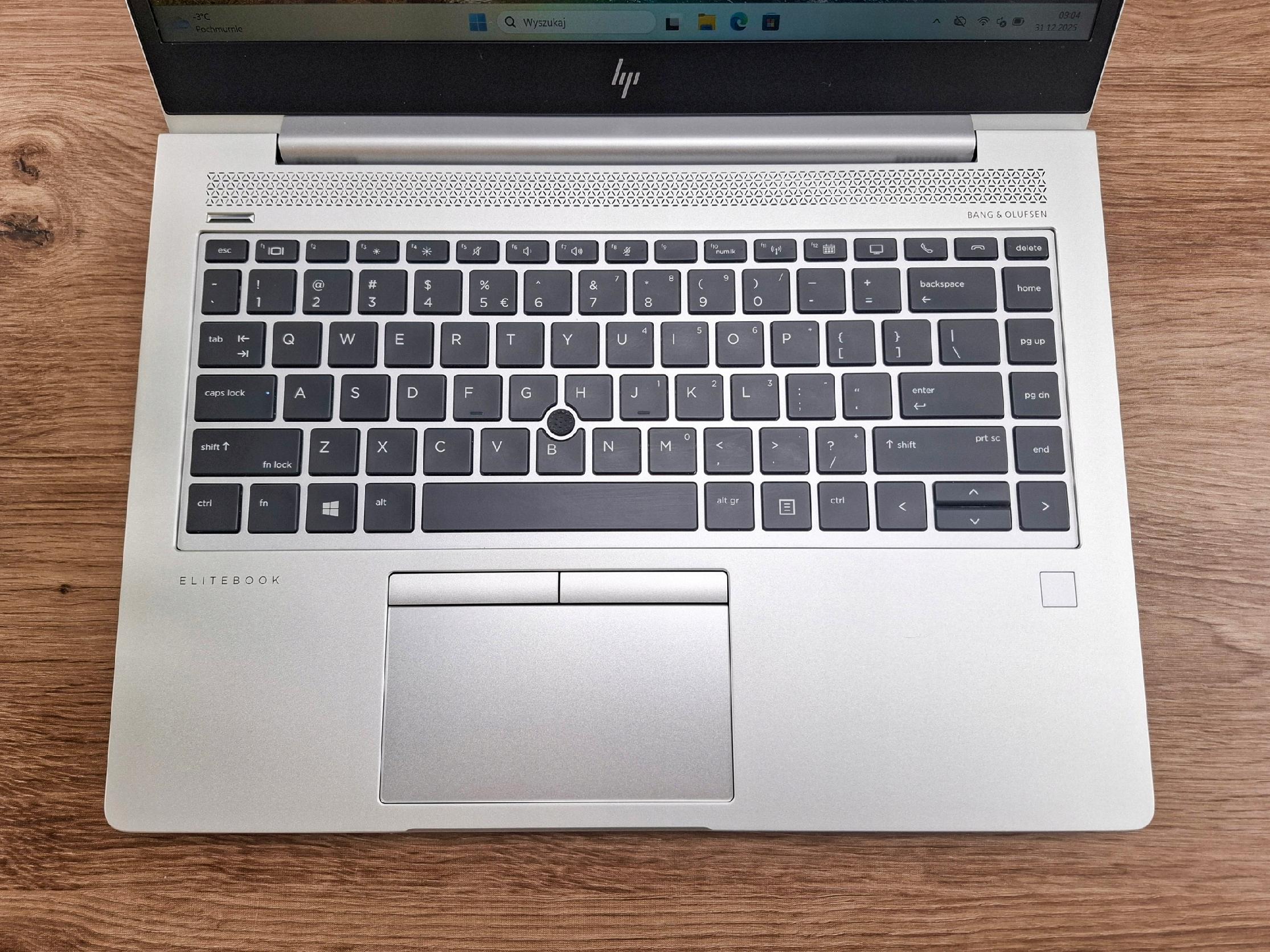 Otwarty laptop HP EliteBook widziany z góry, klawiatura z touchpadem i czytnikiem linii papilarnych na srebrnej obudowie.