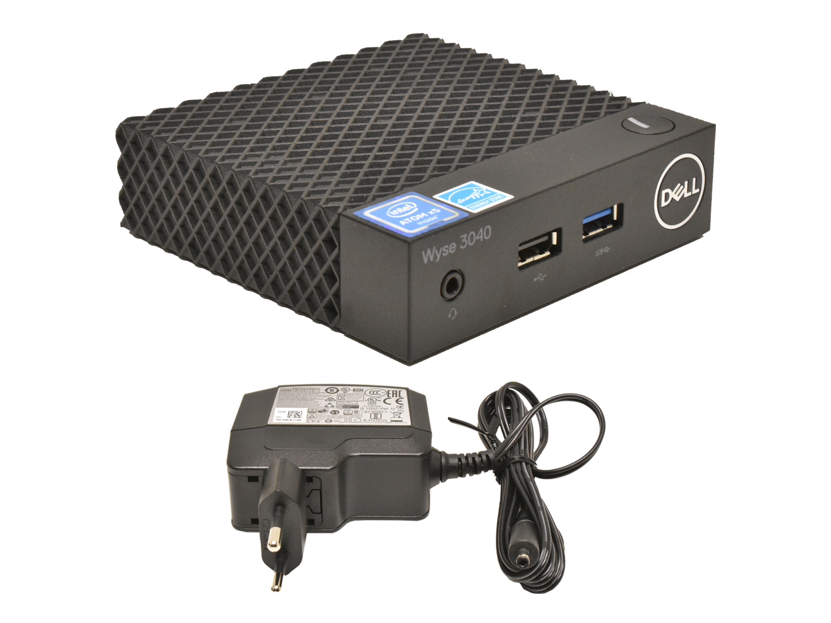 Terminal Dell Wyse 3040 z perforowaną obudową i portem USB na przedzie, poniżej dołączony zasilacz sieciowy z kablem.