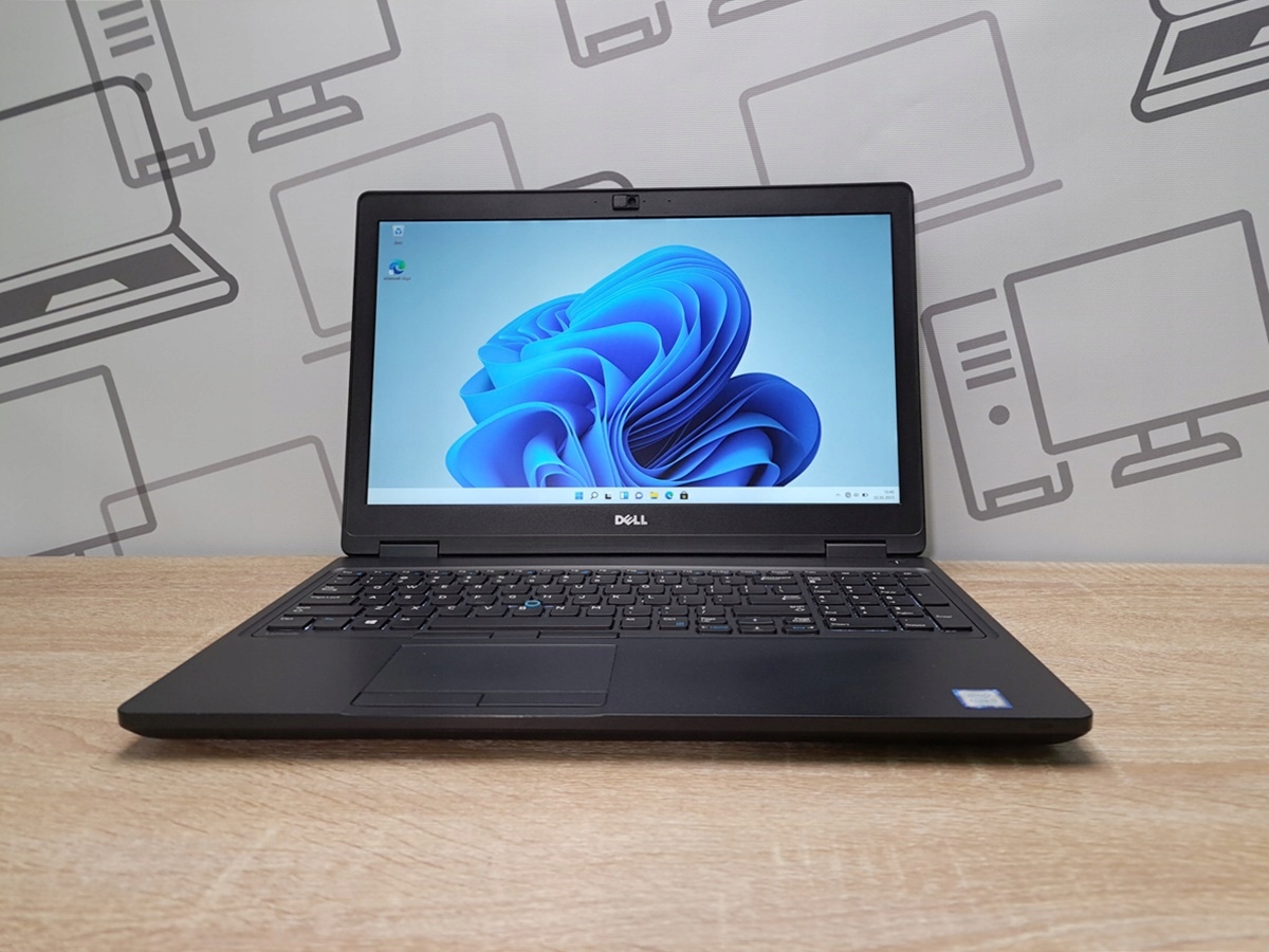 Laptop Dell Latitude 5580 otwarty pod kątem z boku, ekran włączony z logo Windows, widoczna klawiatura i obudowa bez większych śladów użytkowania.