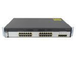 Przedni panel switcha Cisco z 24 portami RJ45 i 4 slotami SFP, na obudowie widoczne żółte naklejki ostrzegawcze.