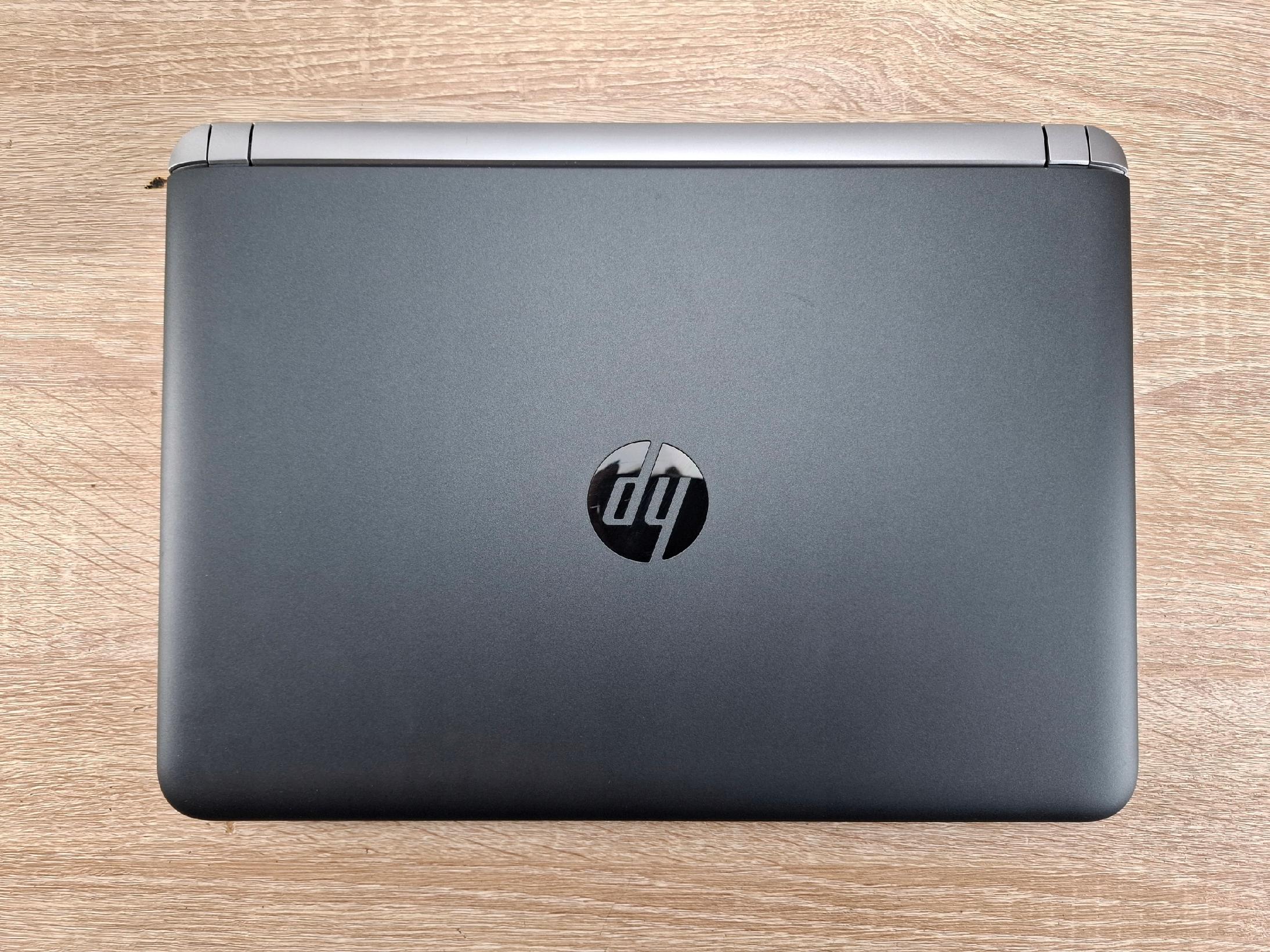 Zamknięta obudowa laptopa HP ProBook widziana od tyłu z logo HP na środku, leżąca na drewnianym blacie.