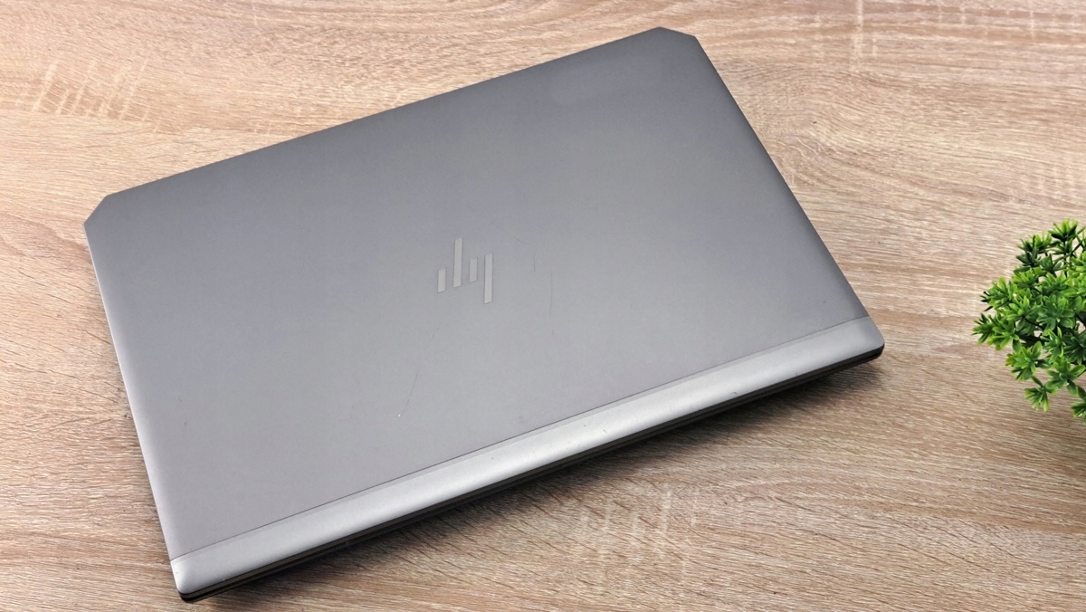 Zamknięty laptop HP ZBook widziany z góry pod kątem, srebrna obudowa na drewnianym blacie.