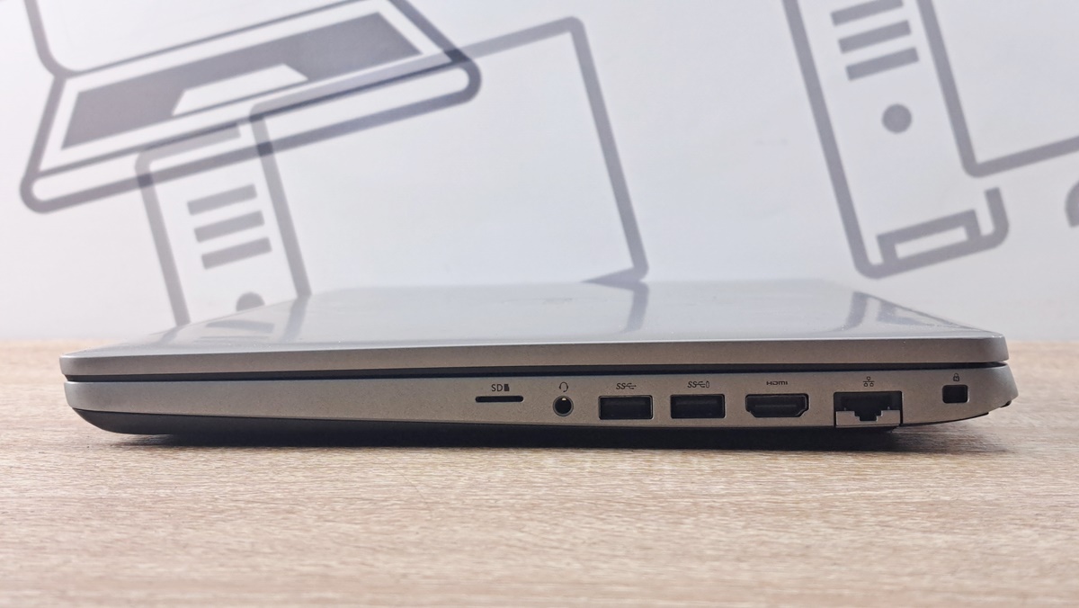 Zamknięty laptop Dell z boku, widoczne porty: czytnik kart, USB, HDMI, RJ45 i slot blokady Kensington.