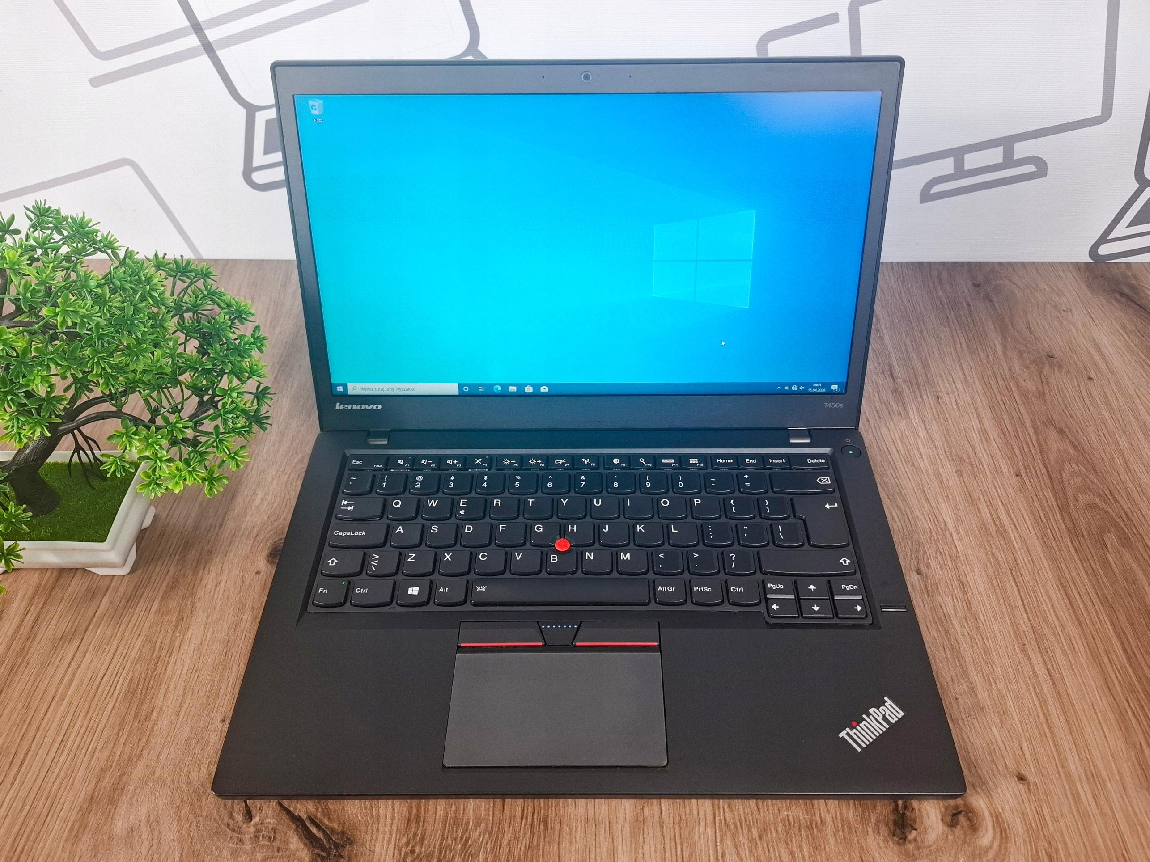 Otwarty laptop Lenovo ThinkPad T450s widziany z przodu, ekran włączony z pulpitem Windows, klawiatura w dobrym stanie.