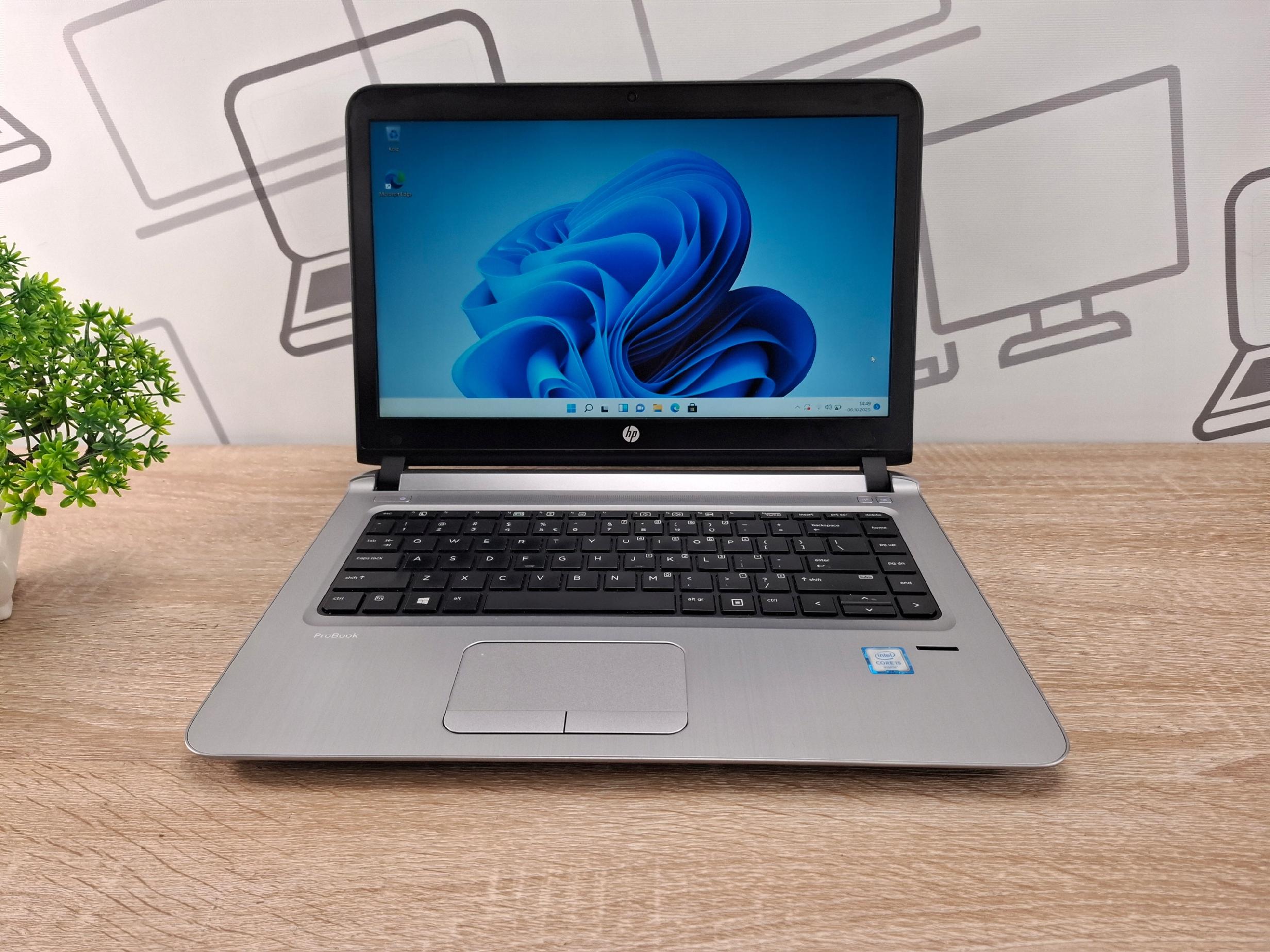 Otwarty laptop HP ProBook 440 G3 pod kątem z przodu, ekran z logo Windows 11, klawiatura widoczna z boku.