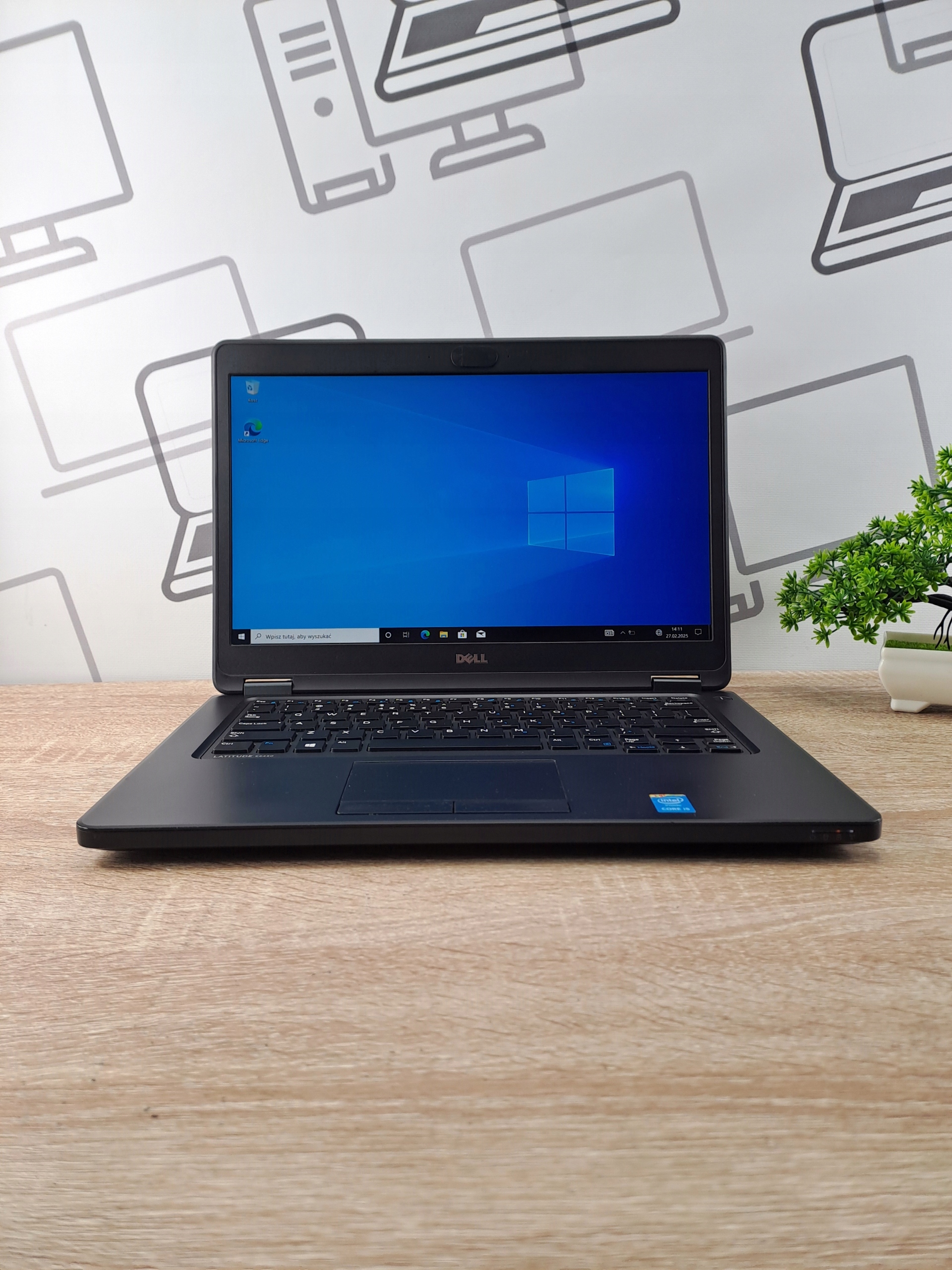 Laptop Dell Latitude otwarty na biurku, ekran włączony z widocznym pulpitem Windows 10
