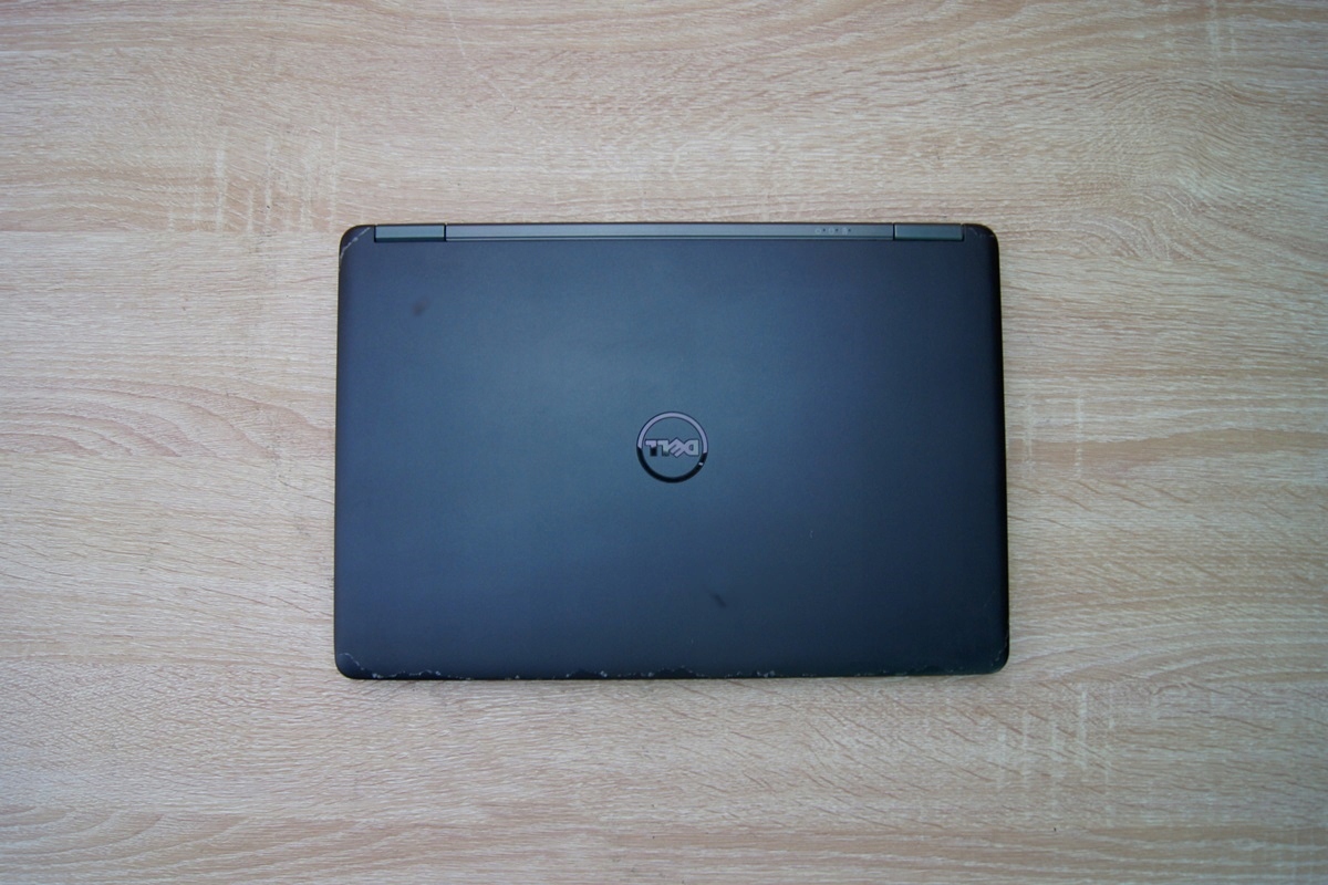 Zamknięty laptop Dell widziany od góry z logo na pokrywie, obudowa z lekkimi śladami użytkowania, na drewnianym blacie.