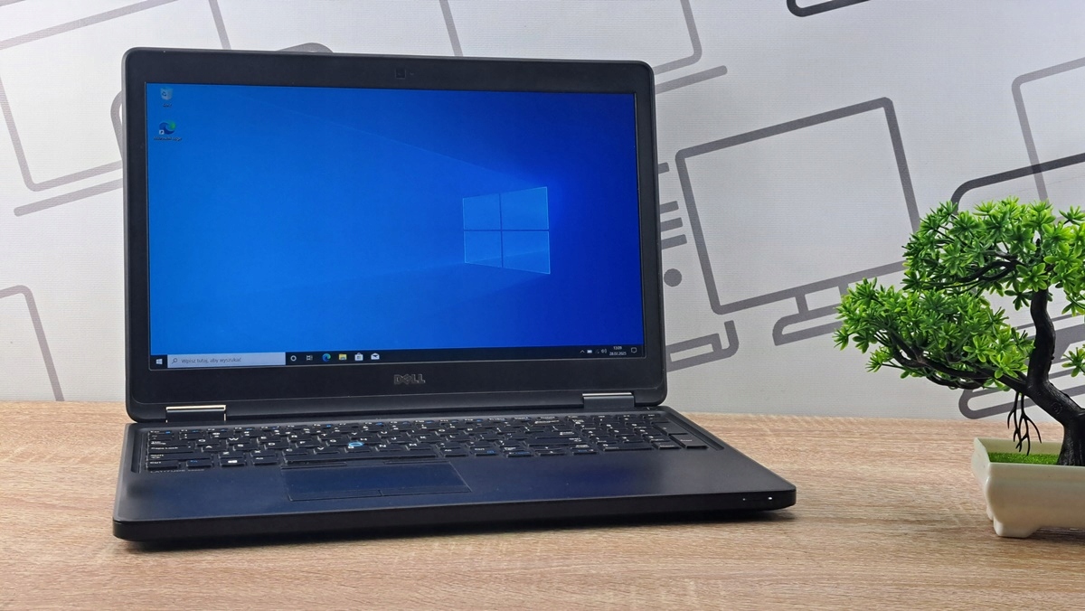 Otwarty laptop Dell Latitude ustawiony pod kątem, na ekranie niebieski pulpit systemu Windows 10.