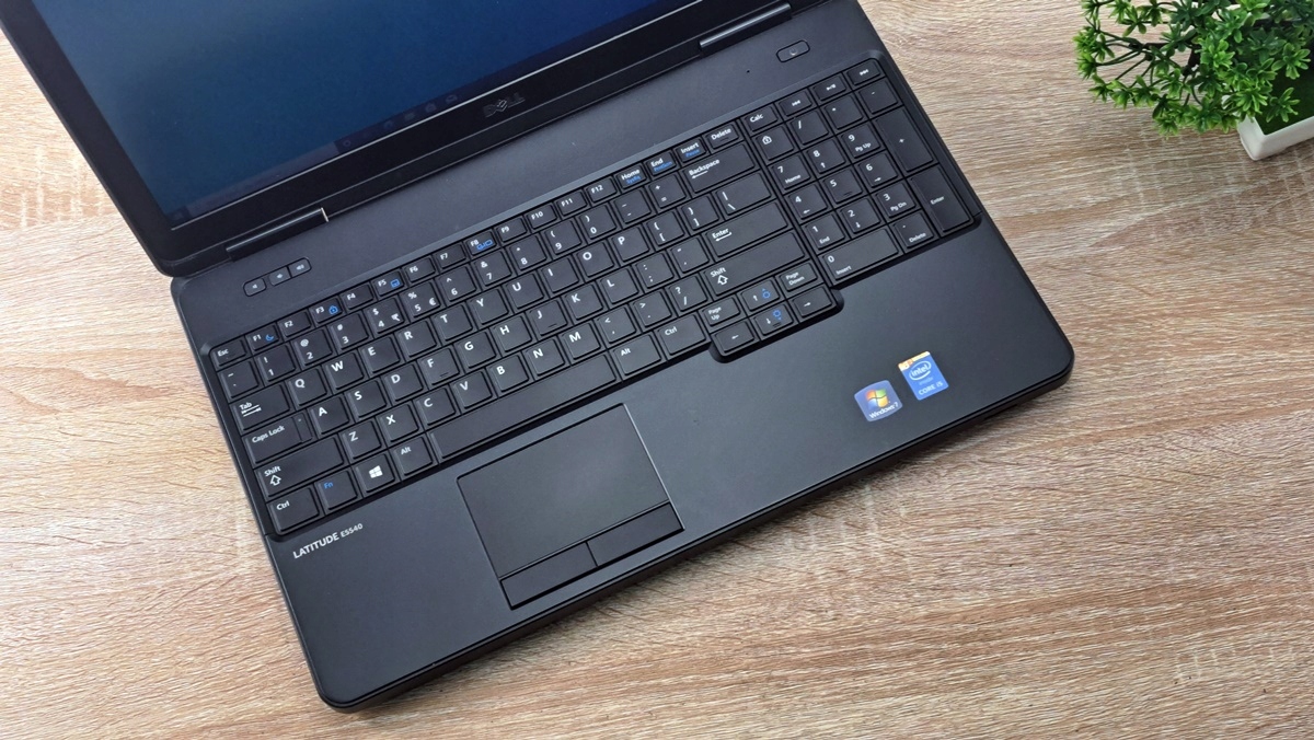 Otwarty laptop Dell Latitude widziany z góry pod kątem, widoczna klawiatura, touchpad i naklejki Intel na obudowie.