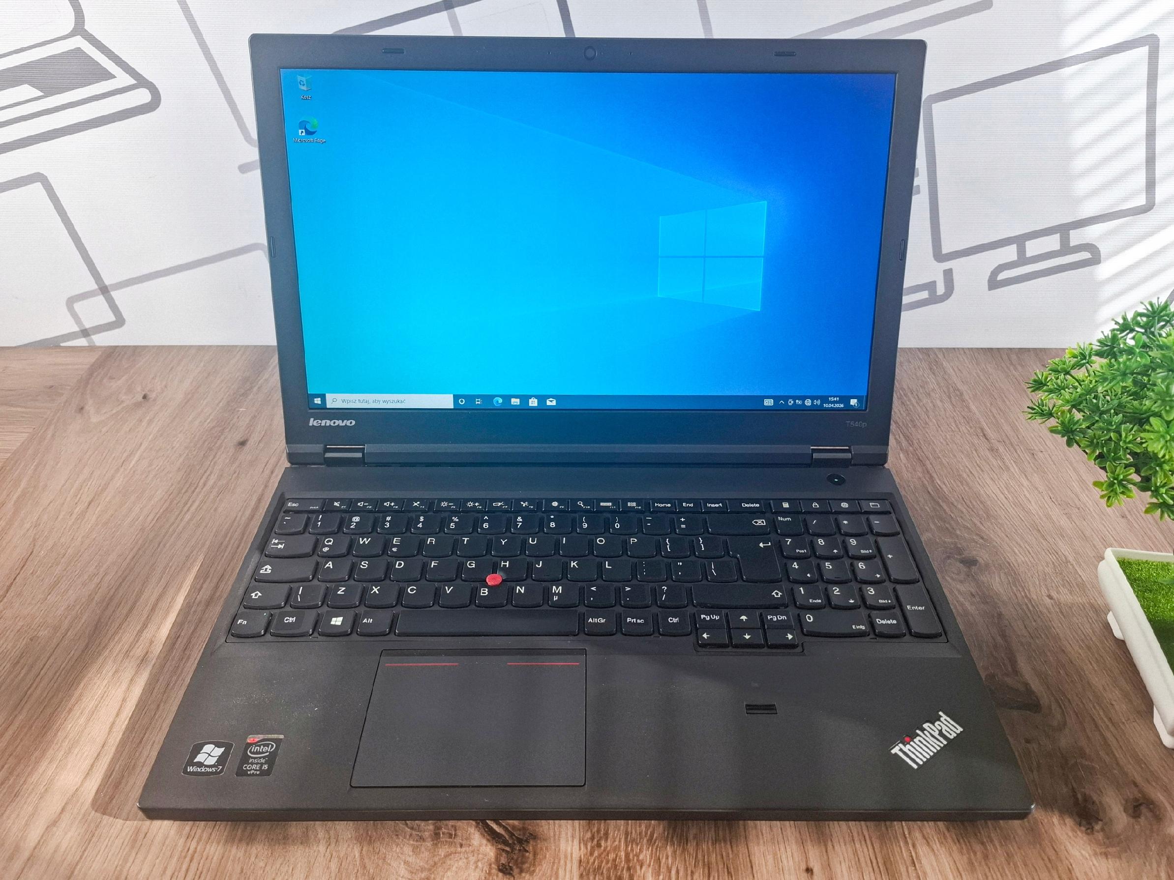 Otwarty laptop Lenovo ThinkPad T540p pod kątem z przodu, ekran włączony z pulpitem Windows 10, klawiatura widoczna.