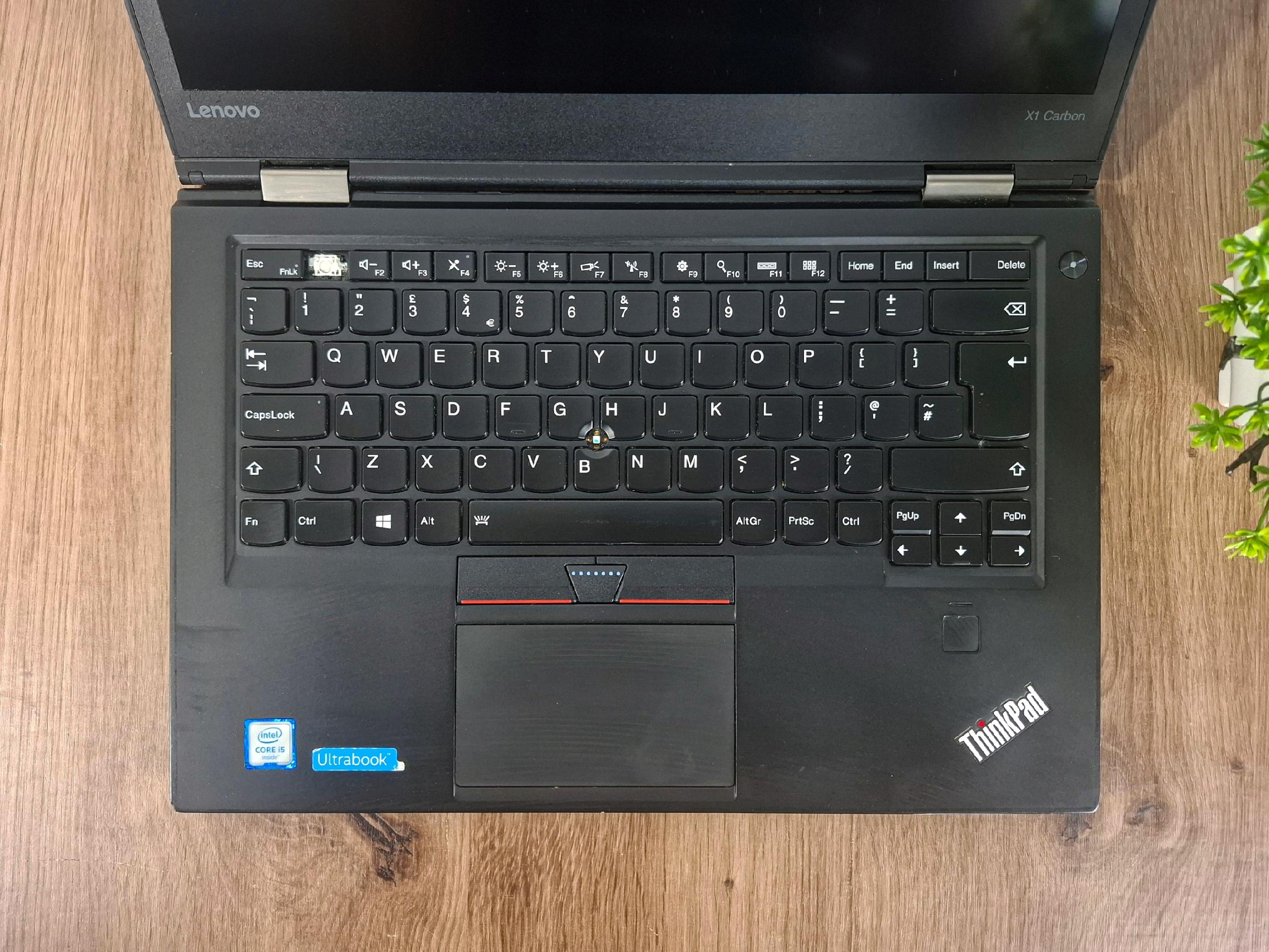 Otwarty laptop Lenovo ThinkPad X1 Carbon widziany z góry, klawiatura i touchpad z widocznymi śladami użytkowania.