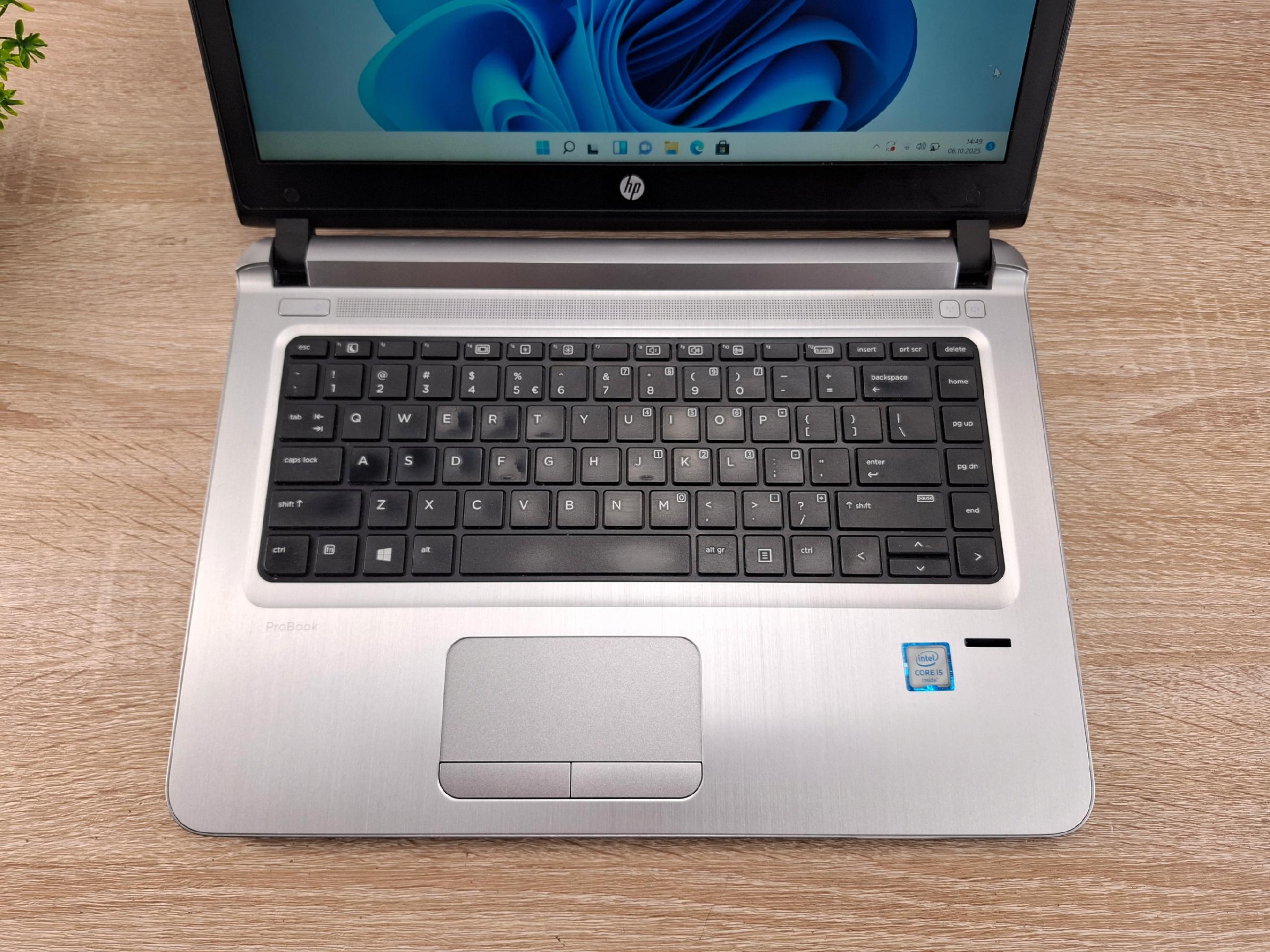 Otwarty laptop HP ProBook widziany z góry pod kątem, ekran z logo Windows, klawiatura i touchpad na blacie z drewna.