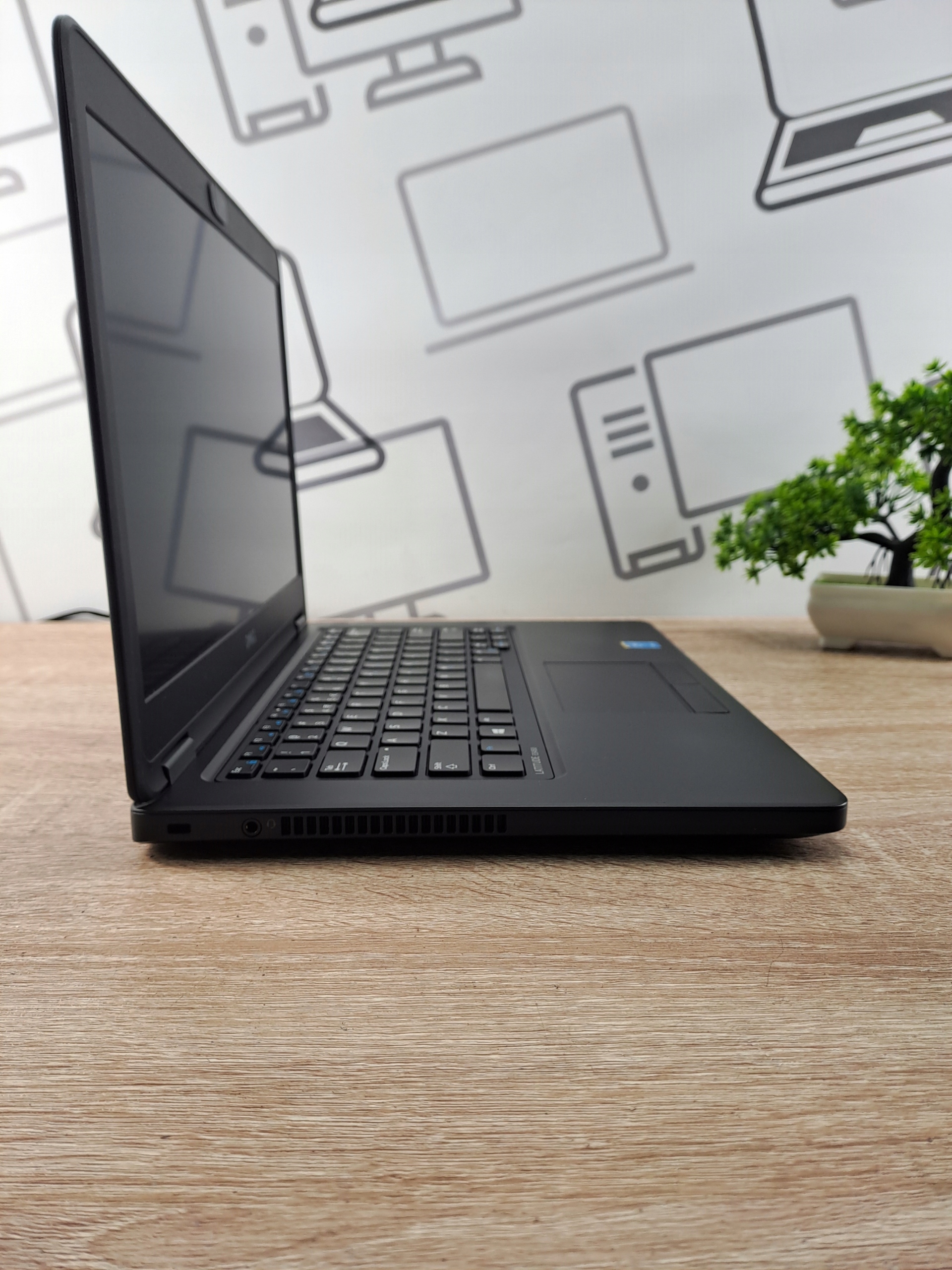 Laptop Dell Latitude E5450 otwarty pod kątem z boku, widoczna klawiatura, ekran wyłączony, obudowa czarna matowa.