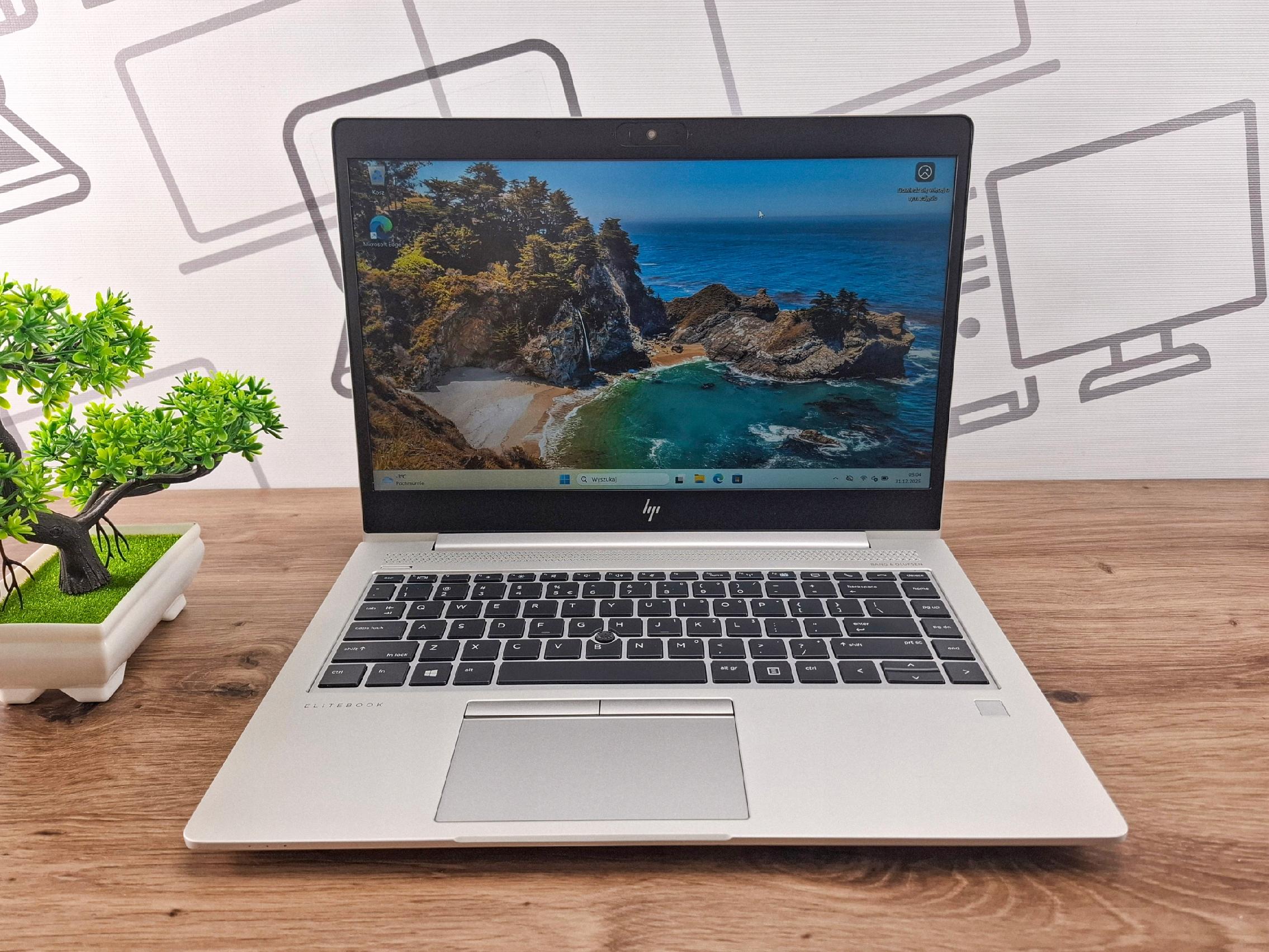 Otwarty laptop HP EliteBook widziany z przodu pod kątem, na ekranie tapeta z klifem nad morzem, obudowa w kolorze srebrnym.