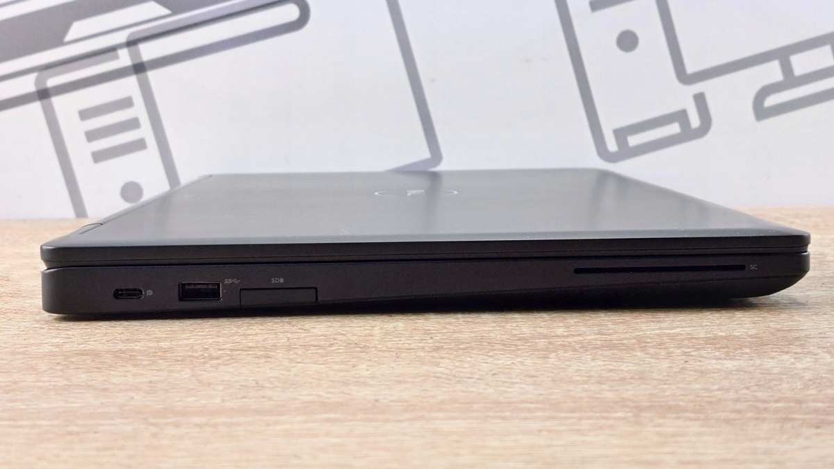 Zamknięty laptop Dell Latitude 5590 z boku, widoczne porty USB-C, USB-A oraz czytnik kart, obudowa lekko przetarta.