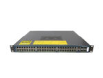 Przedni panel switcha Cisco z czterema rzędami portów RJ45, żółtą naklejką ostrzegawczą i uszami montażowymi.