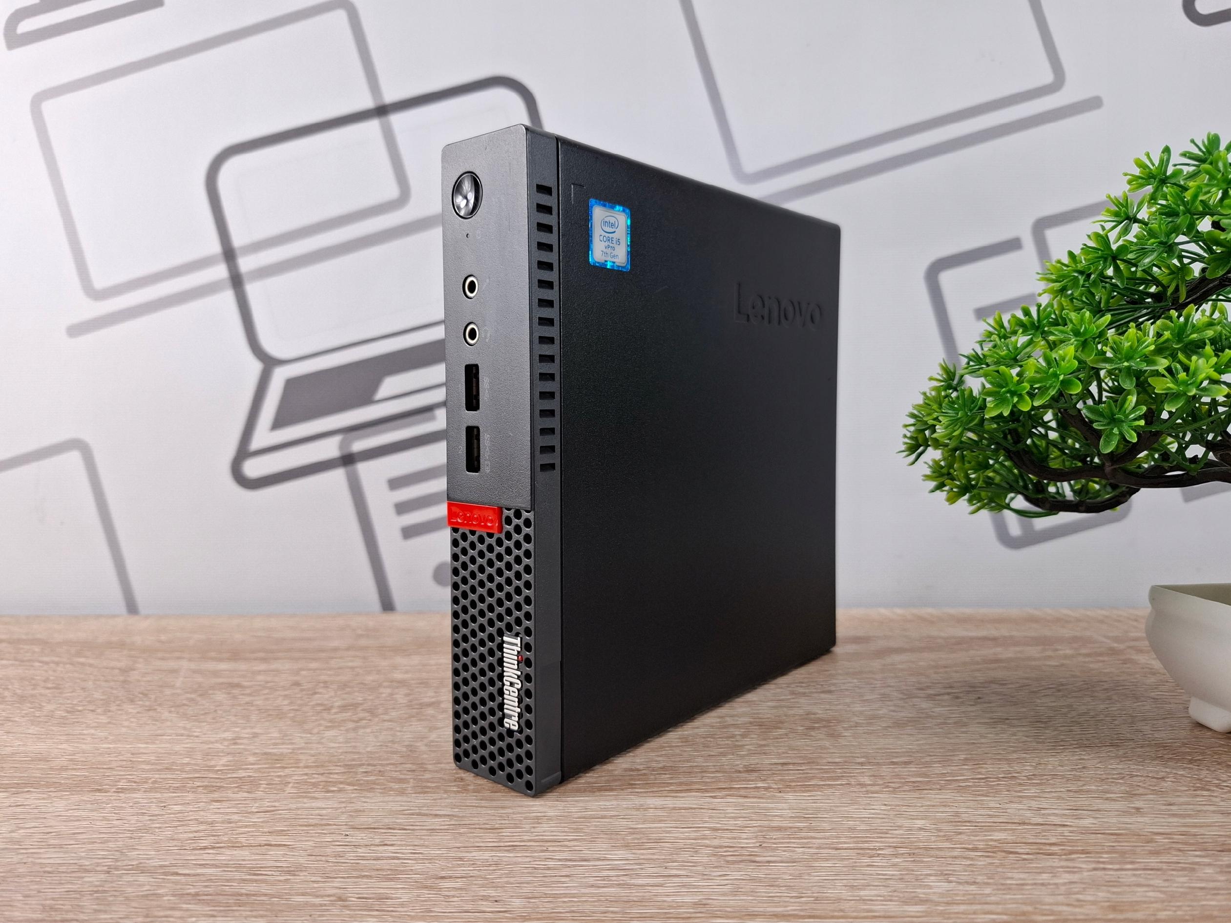 Komputer Lenovo ThinkCentre M910Q Tiny ustawiony na krótszym boku, widoczne porty USB i przycisk zasilania na przednim panelu.