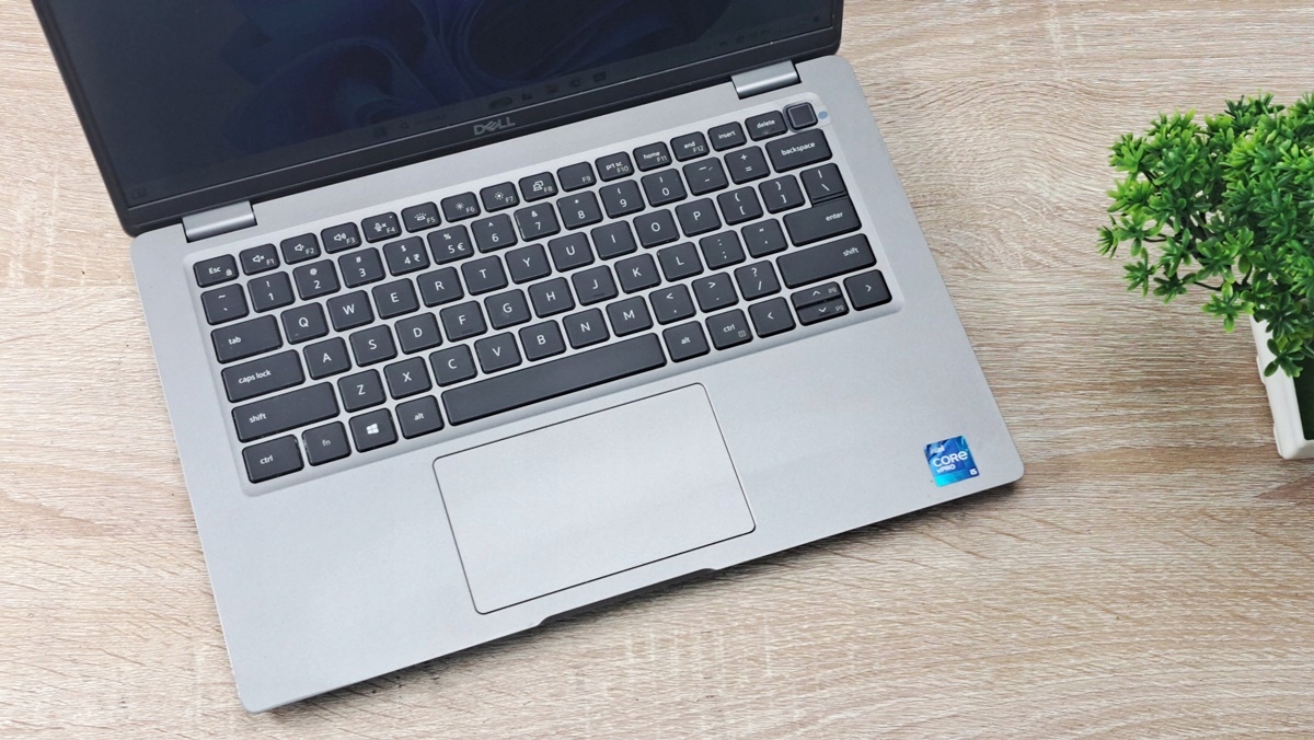 Laptop Dell uchylony pod kątem z góry, widoczna klawiaturka, touchpad i naklejka Intel Core i5 na obudowie.