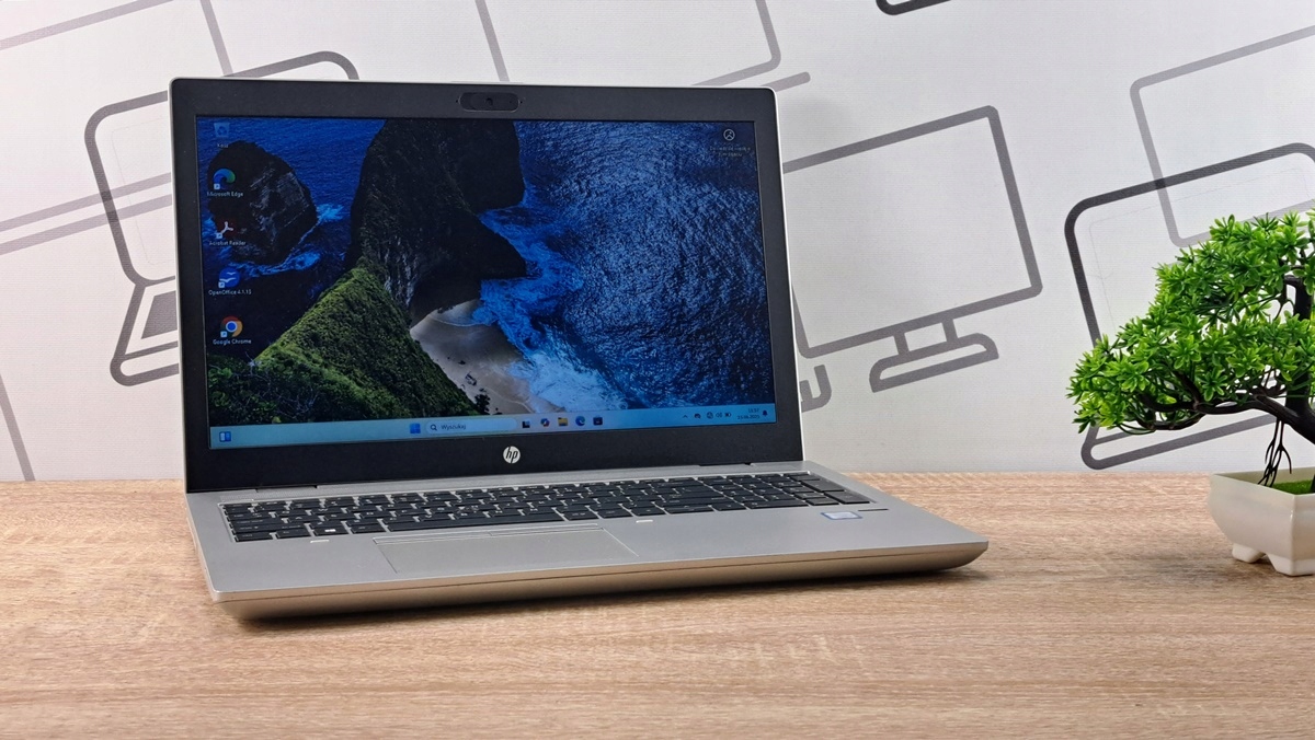Otwarty laptop HP ProBook z boku pod kątem, na ekranie tapeta z niebieskim wzorem, obudowa w kolorze srebrnym.