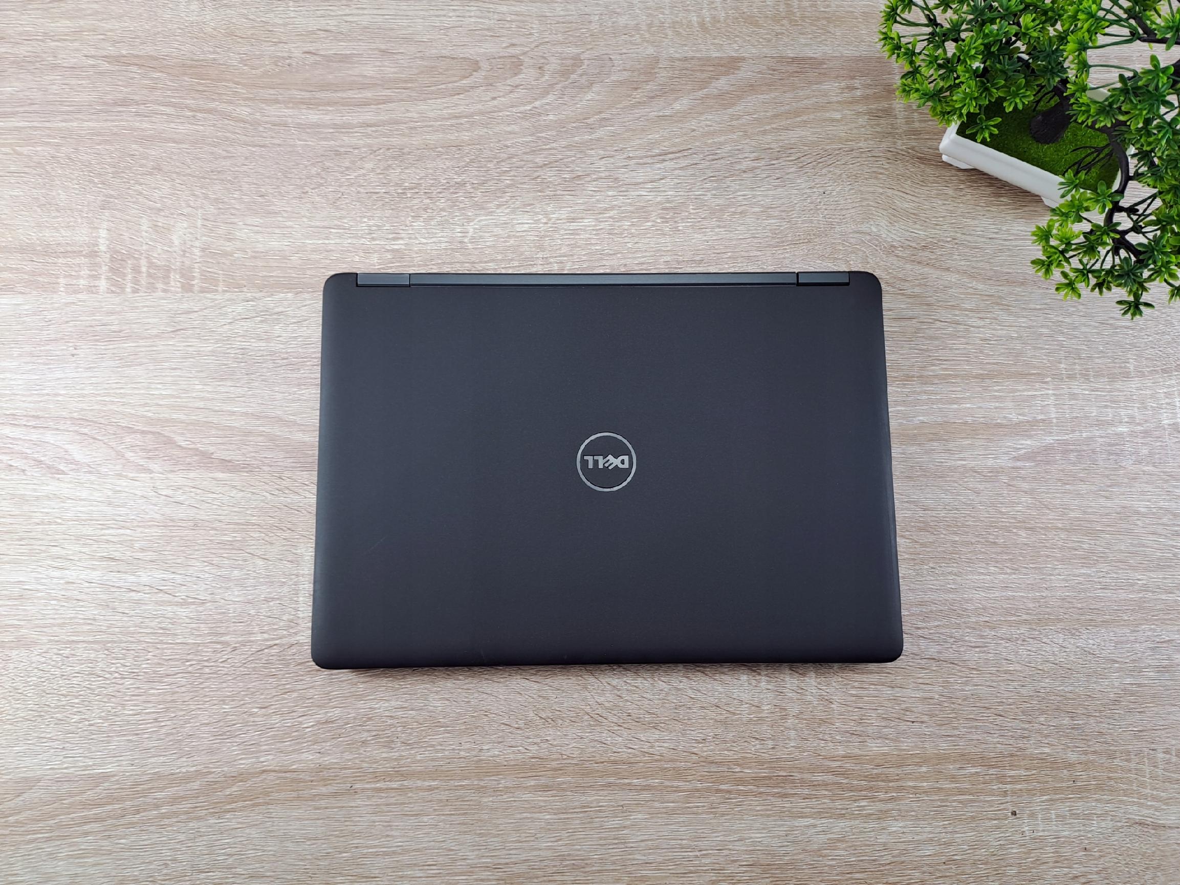 Zamknięta pokrywa laptopa Dell z logo pośrodku, widok z góry na czarnej matowej obudowie.