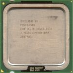 Zbliżenie procesora Intel Pentium 4 na zielonej płytce, widoczna metalowa powierzchnia z opisem modelu i drobne zabrudzenia.