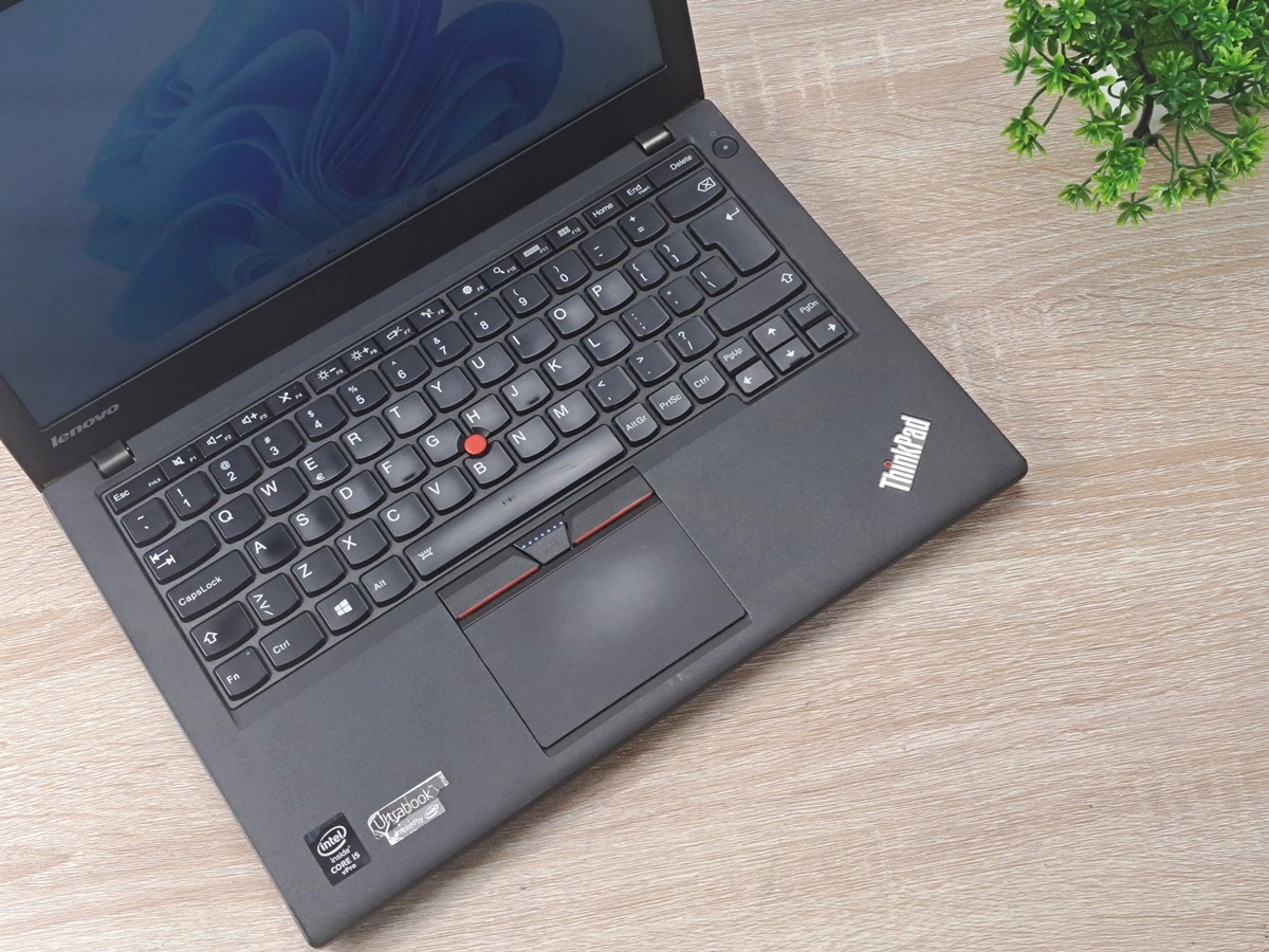 Otwarty laptop Lenovo ThinkPad X250 z góry, widoczna klawiatura z czerwonym trackpointem i touchpad.