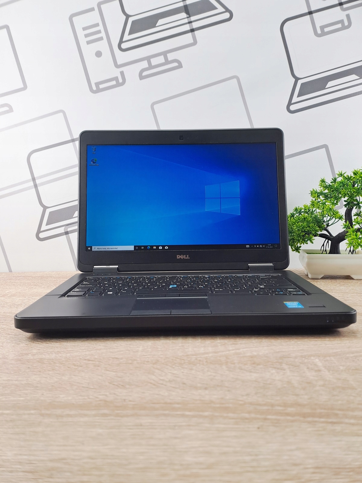 Laptop Dell Latitude otwarty pod kątem z przodu, na ekranie pulpit Windows 10, obudowa czarna z widocznymi śladami użytkowania