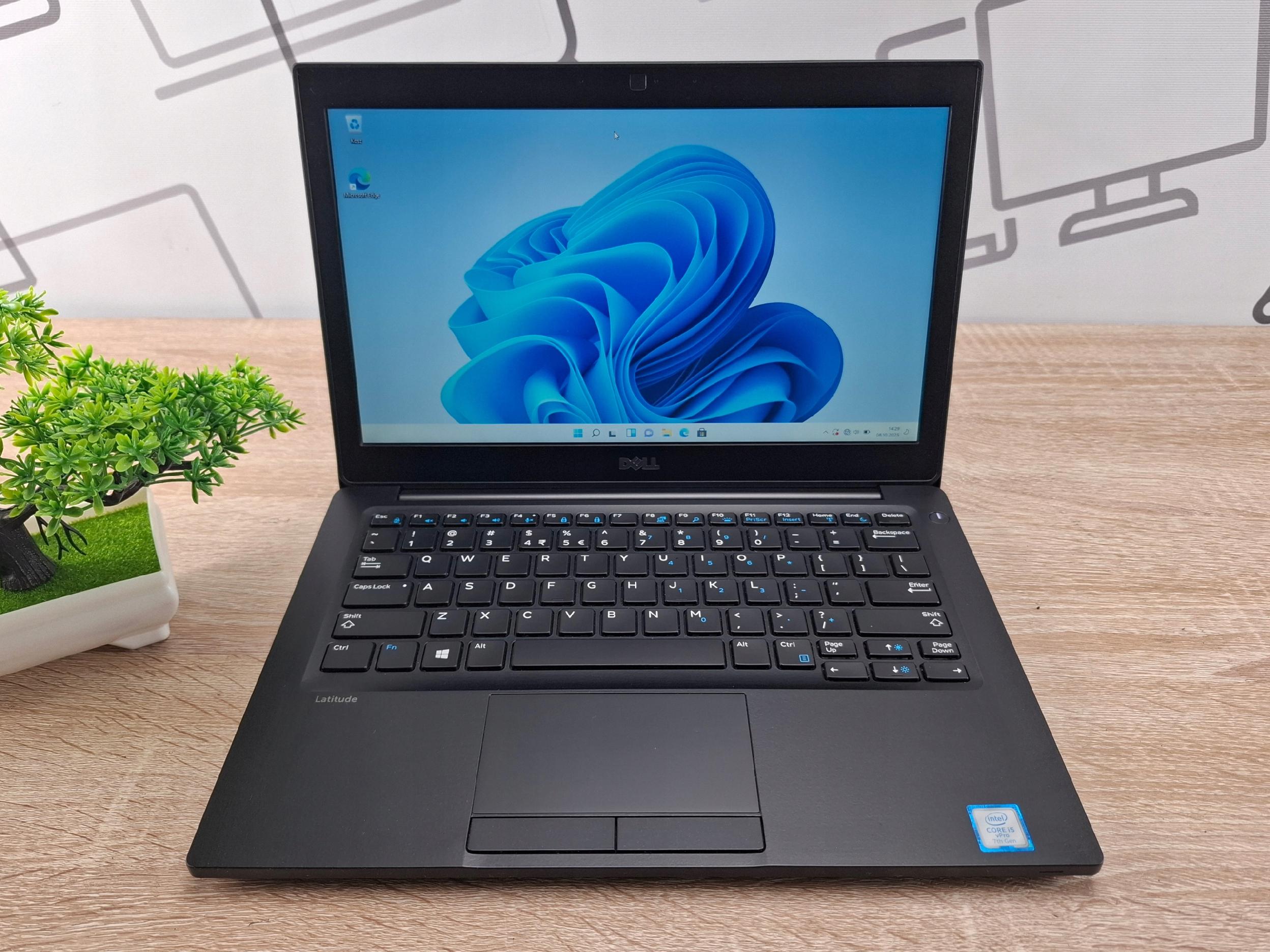 Otwarty laptop Dell Latitude 7280 pod kątem z boku, ekran włączony z logo Windows 11, klawiatura i touchpad widoczne.