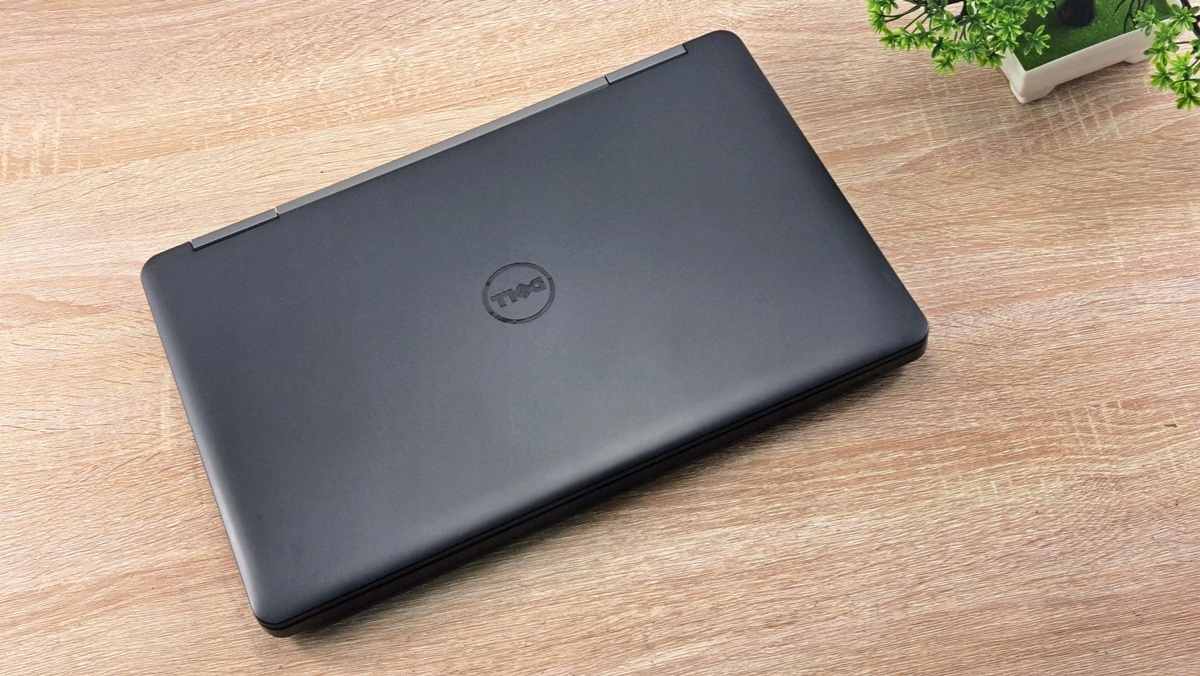 Zamknięty laptop Dell Latitude z logo na pokrywie, widok z góry pod kątem na drewnianym blacie