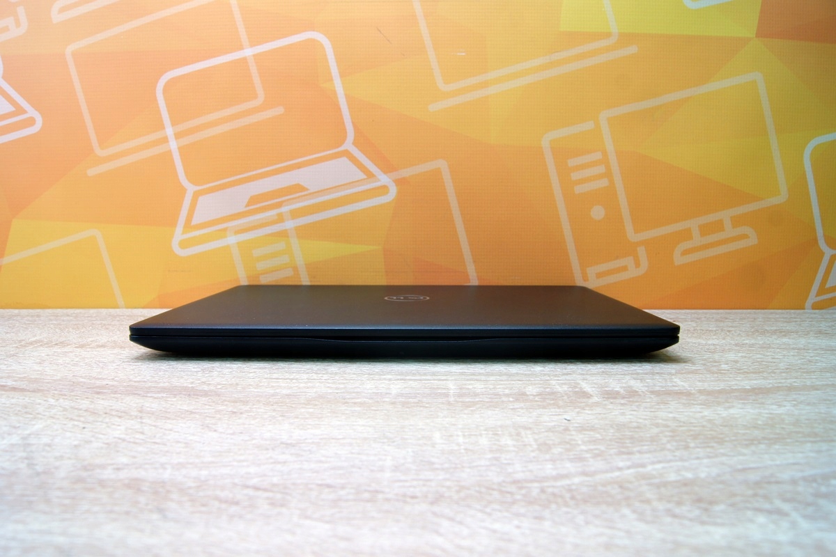 Zamknięty laptop Dell Latitude widoczny z boku, cienka krawędź obudowy na blacie, bez widocznych portów.