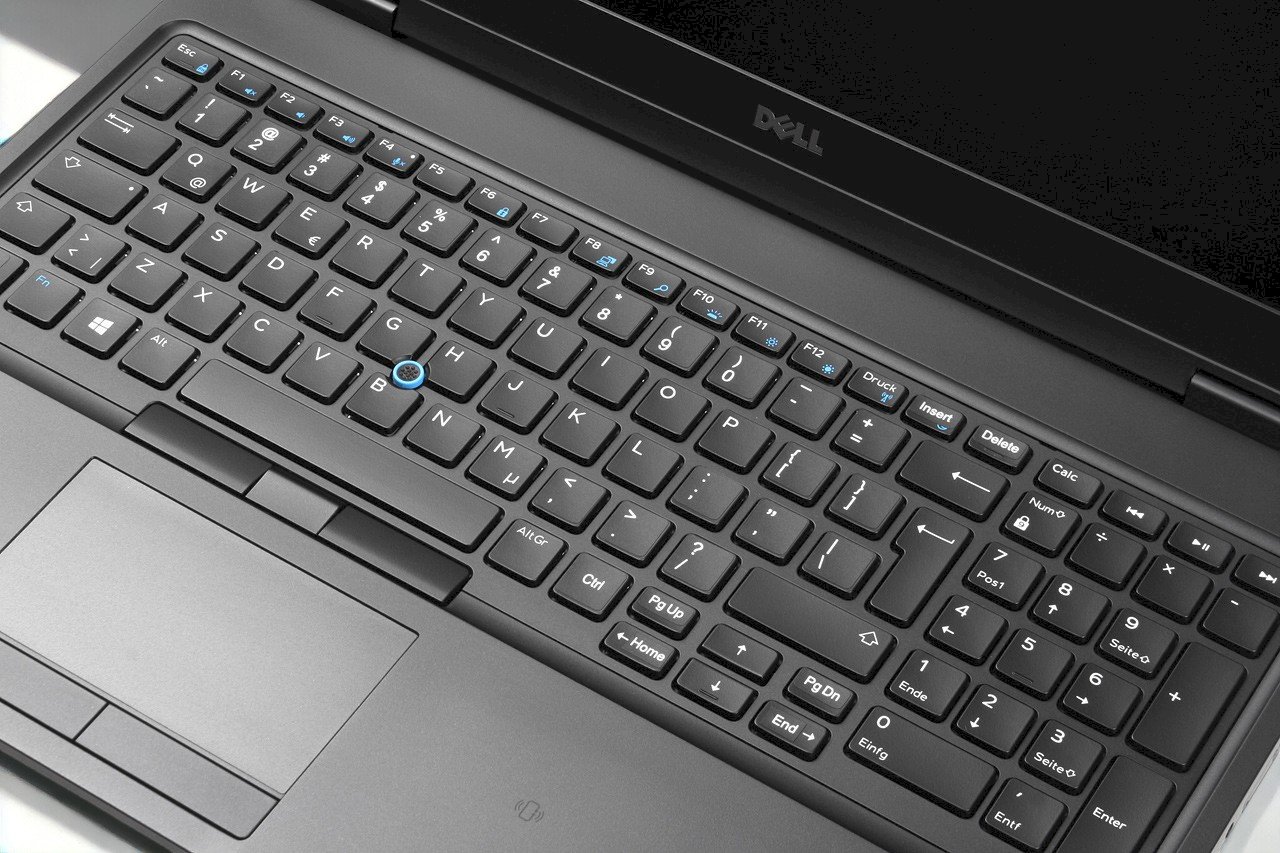 Zbliżenie na klawiaturę laptopa Dell Latitude z czerwonym trackpointem i touchpadem, widoczne niewielkie przetarcia klawiszy.