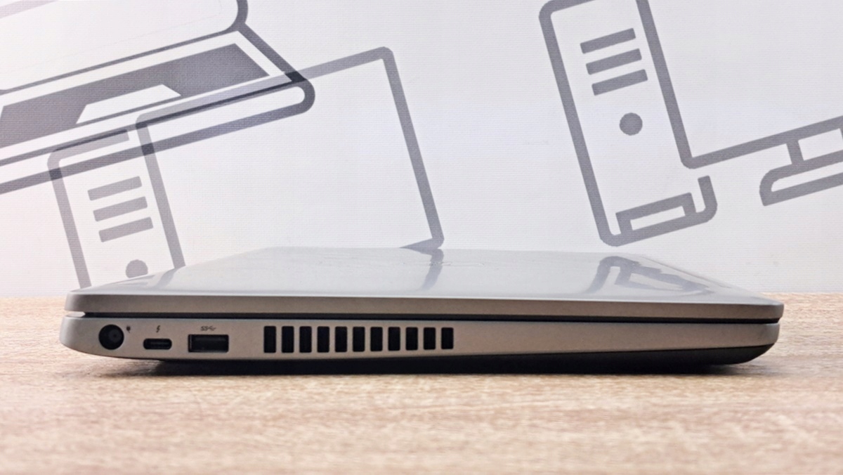 Zamknięty laptop Dell w widoku z boku z portem zasilania, USB-C i otworami wentylacyjnymi, obudowa lekko zmatowiała.