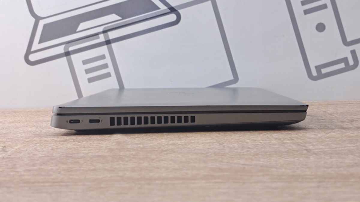 Zamknięty laptop Dell z boku, widoczny port USB-C i otwory wentylacyjne, obudowa lekko zarysowana.