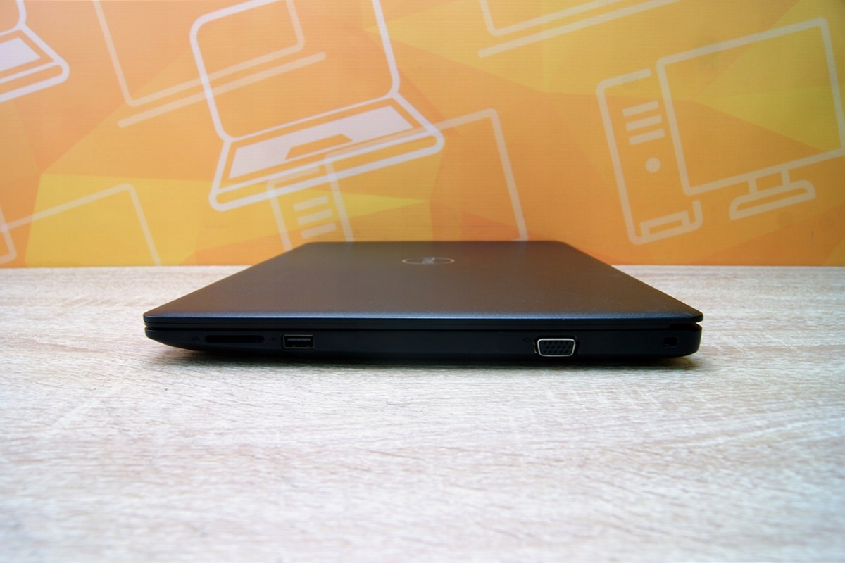 Zamknięty laptop Dell Latitude 3490 z boku, widoczna szczelina na kartę i złącze zasilania na cienkiej krawędzi obudowy.