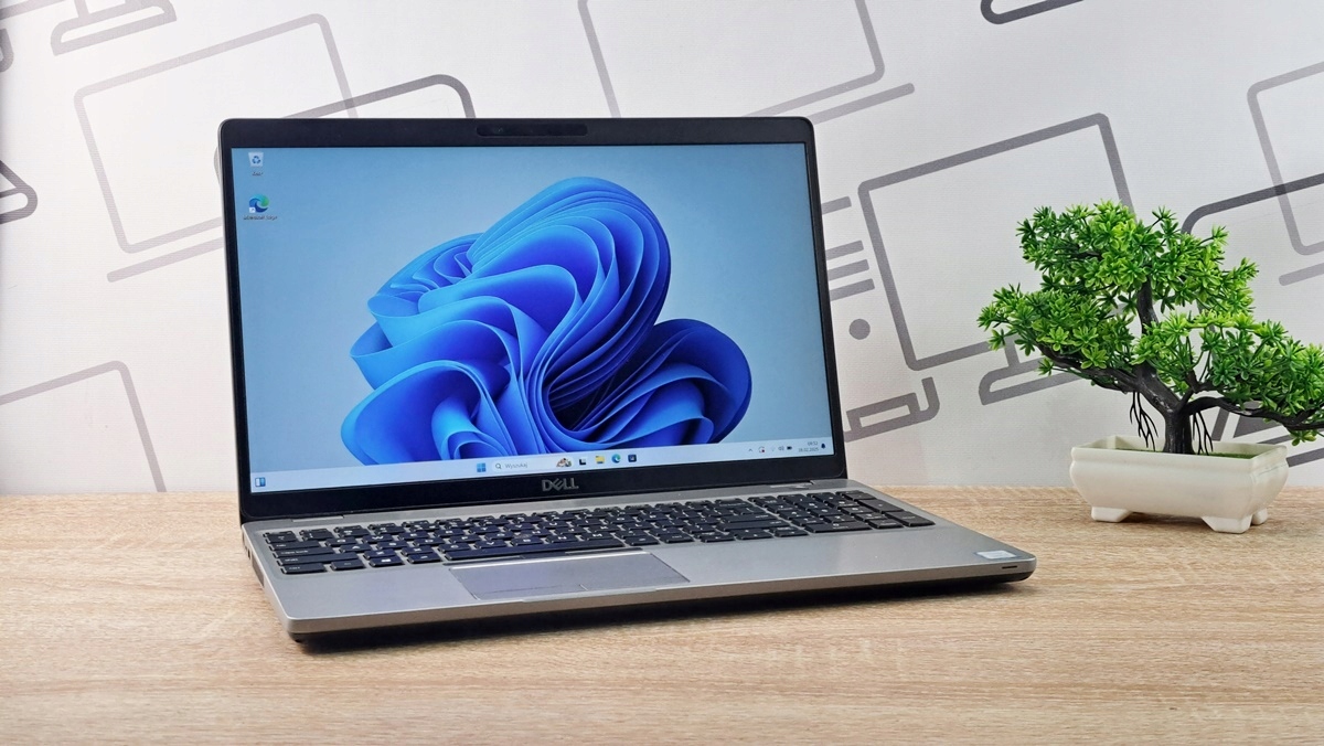 Otwarty laptop Dell Latitude ustawiony pod kątem, na ekranie widoczna kolorowa tapeta systemu Windows 11.