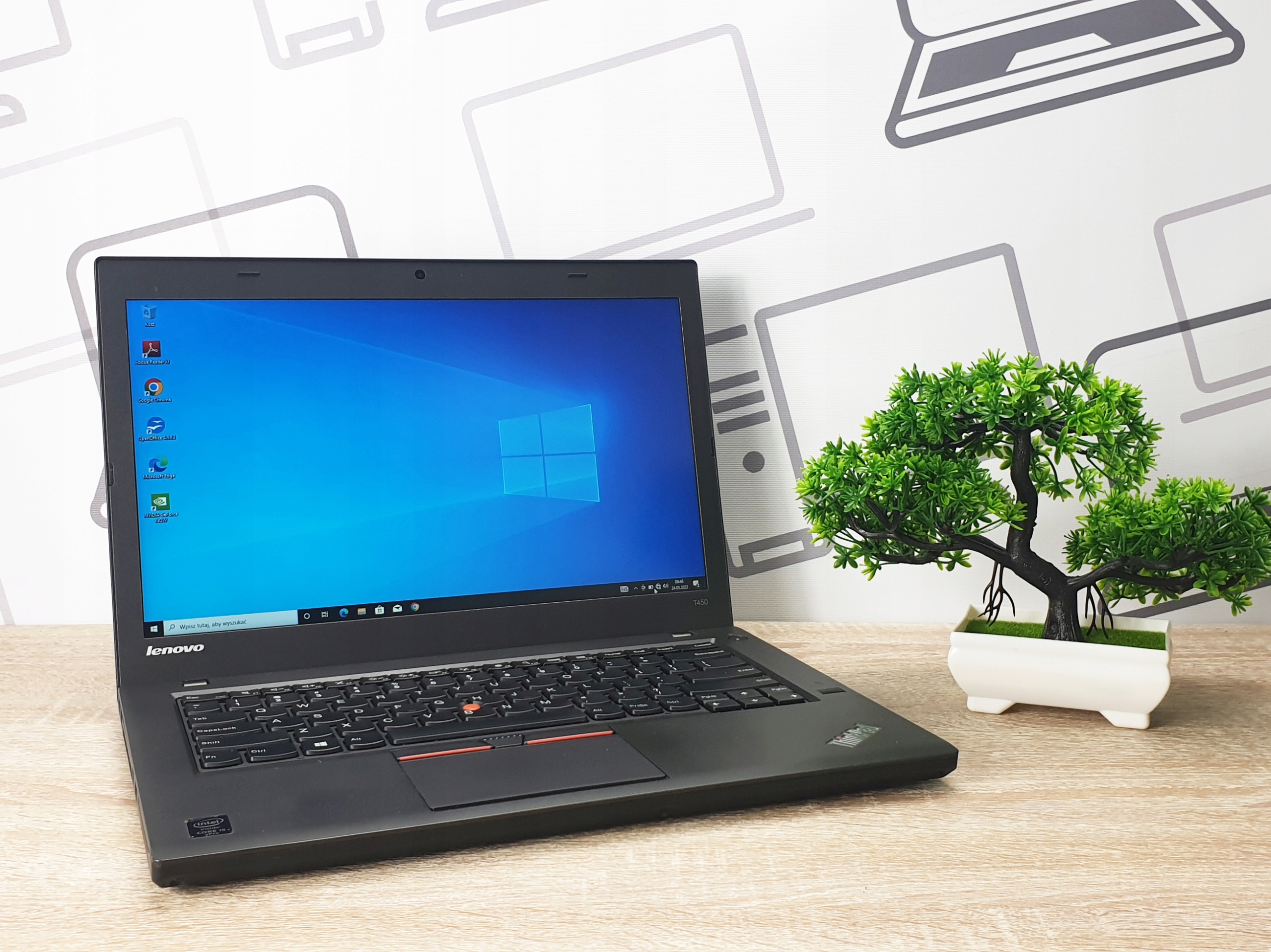 Otwarty laptop Lenovo ThinkPad T450 z boku, ekran z pulpitem Windows 10, obok bonsai na biurku.