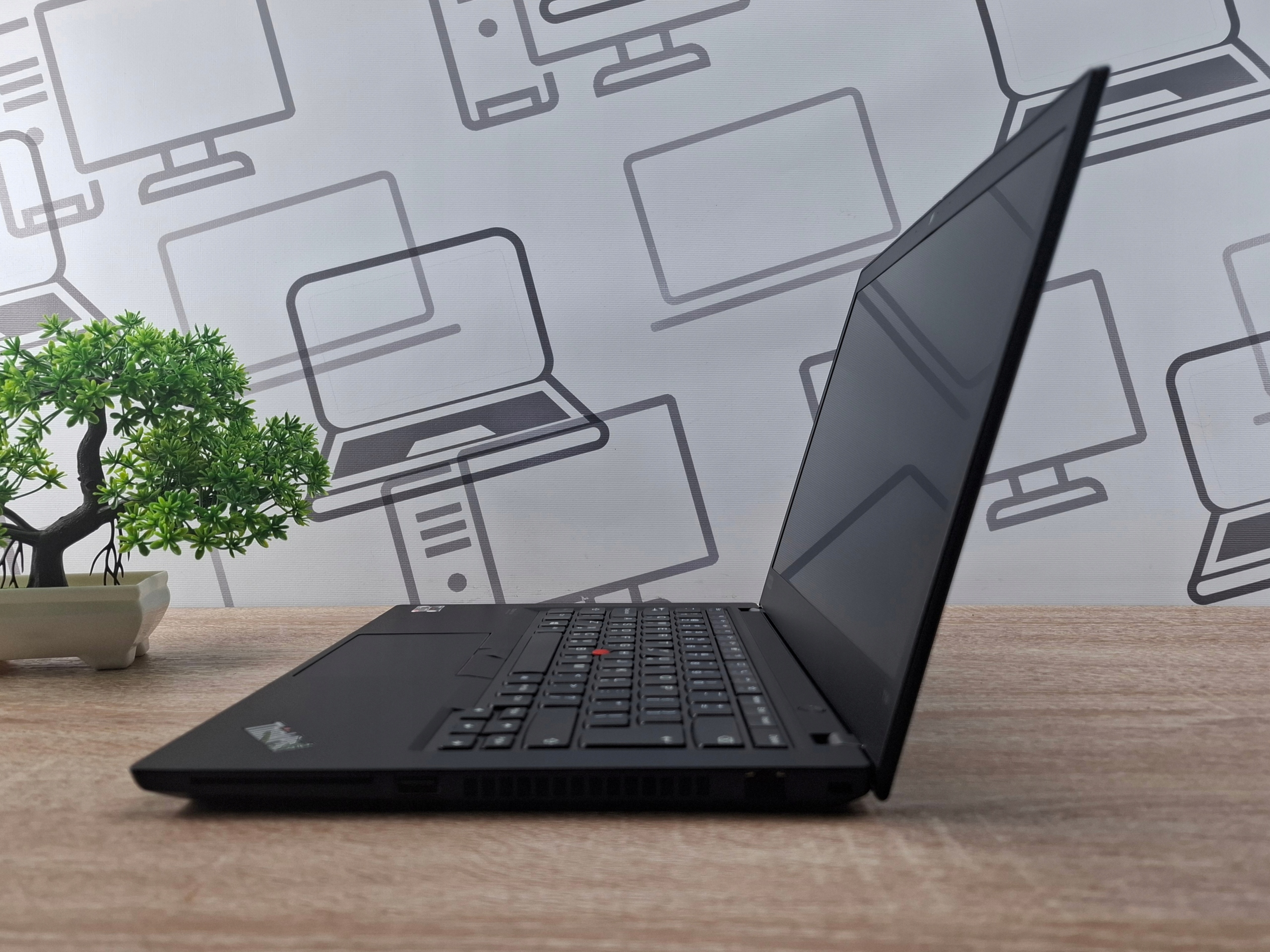 Laptop Lenovo ThinkPad T14 otwarty pod kątem z boku, widok na klawiaturę i tył ekranu, obudowa czarna.