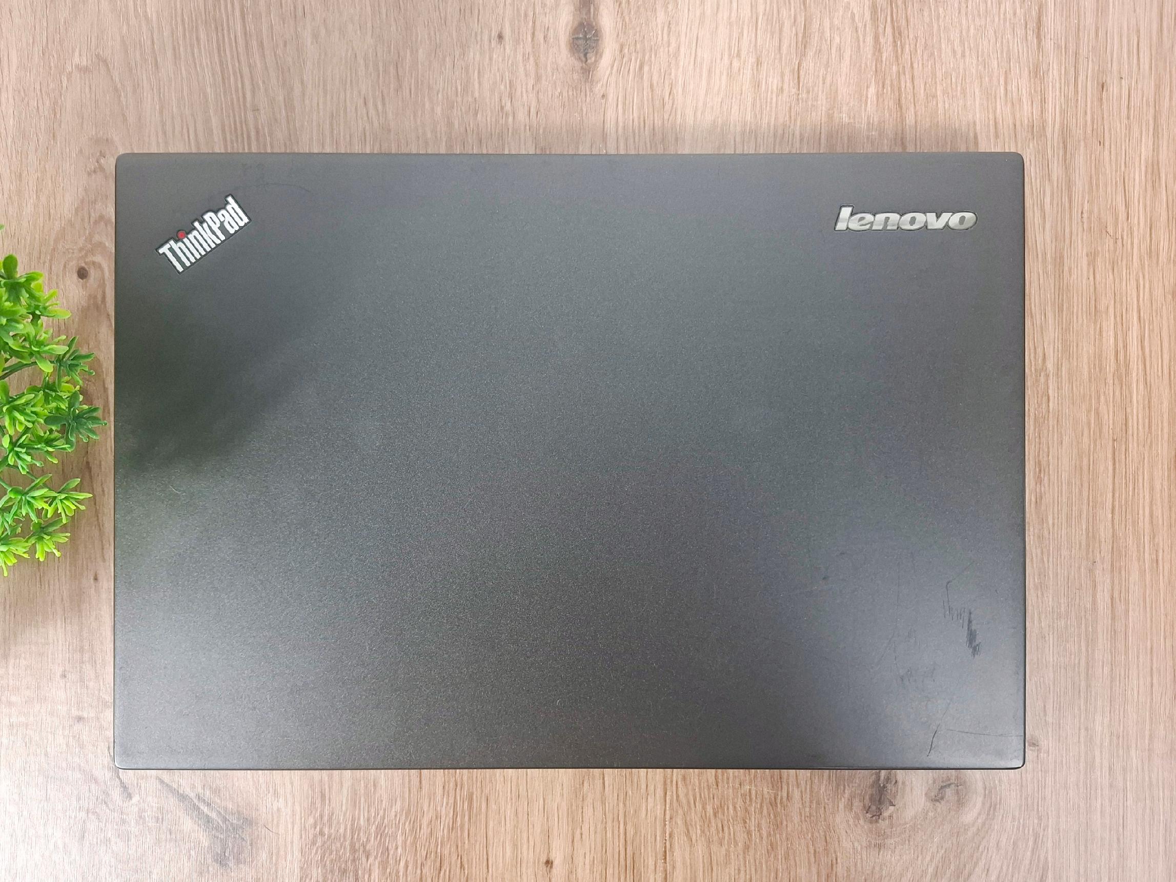 Zamknięta klapa laptopa Lenovo ThinkPad z widocznymi logo, matowa czarna obudowa z lekkimi zarysowaniami.