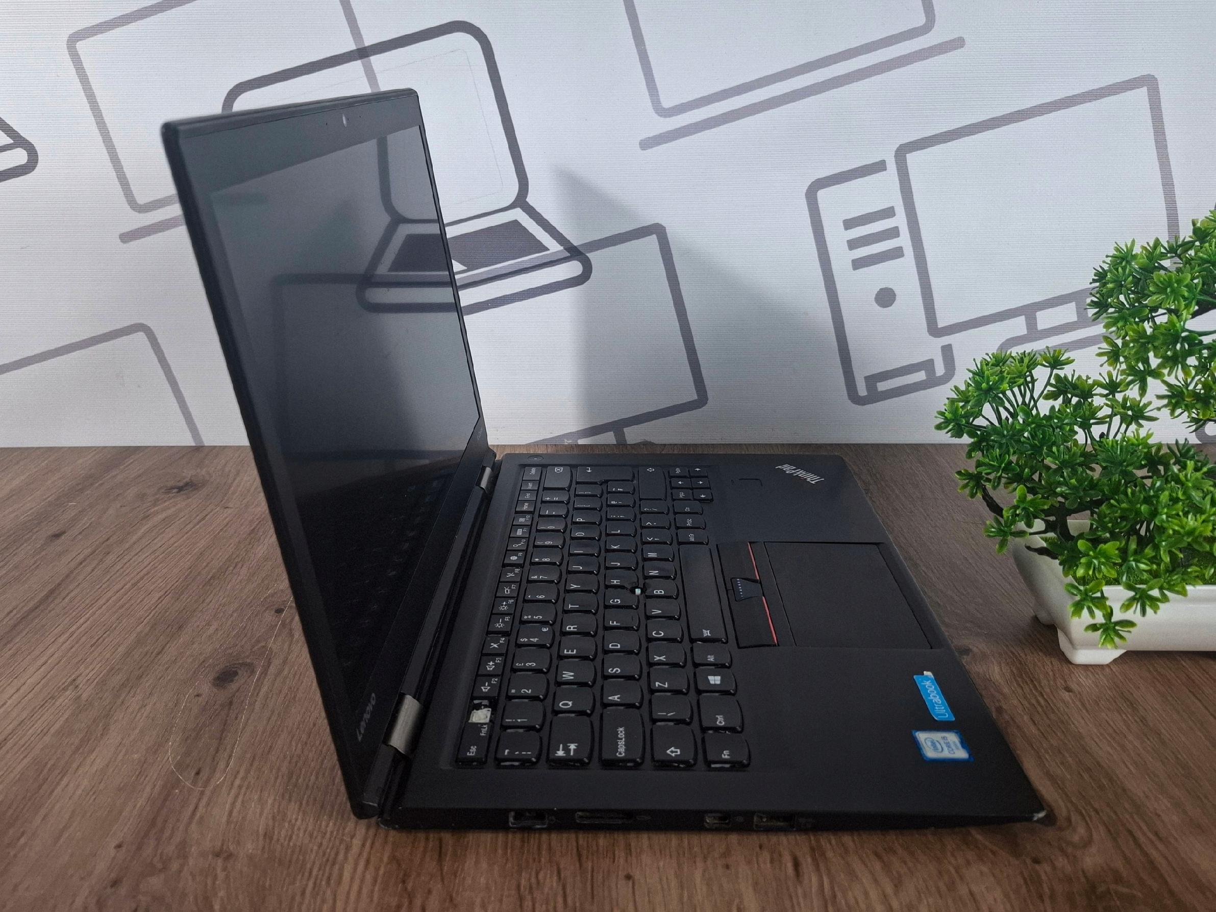 Laptop Lenovo ThinkPad X1 Carbon otwarty pod kątem z boku, widoczna klawiatura i wygaszony ekran, obudowa lekko przetarta na krawędziach.