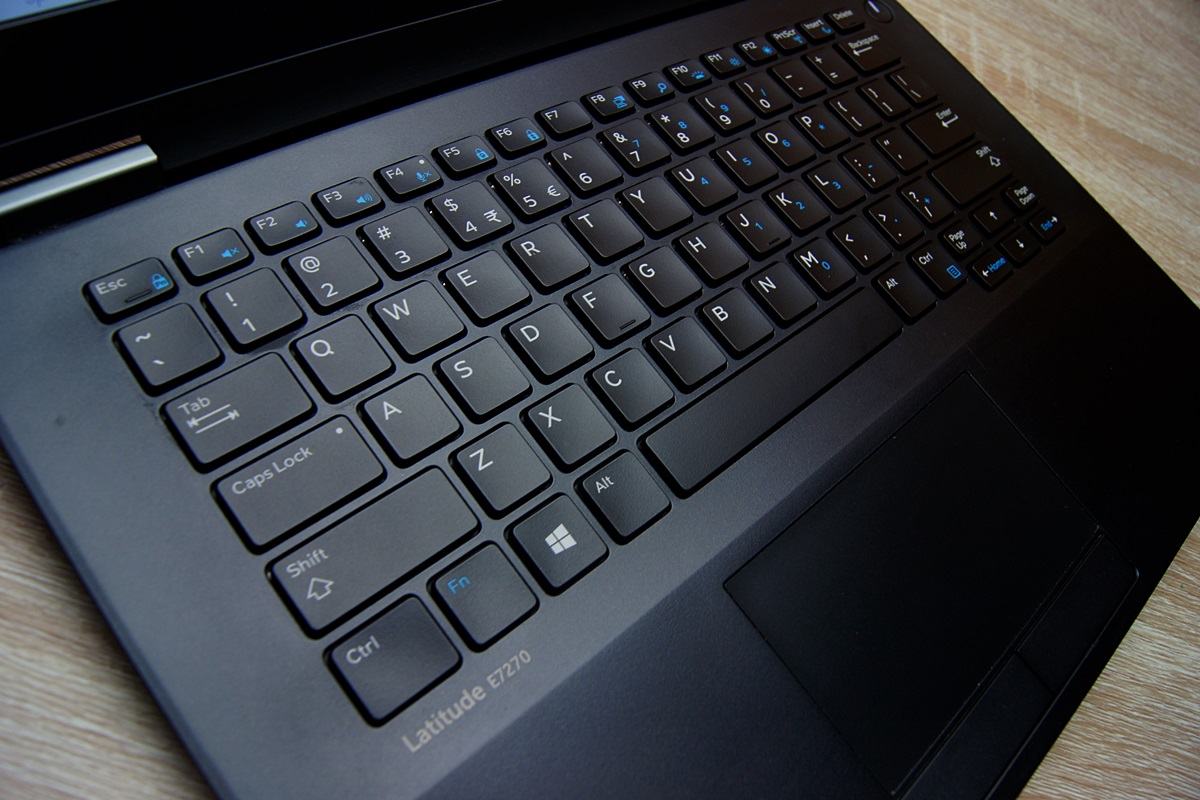 Zbliżenie na klawiaturę laptopa Dell z lewej strony pod kątem, widoczne podświetlenie klawiszy i gładzik.