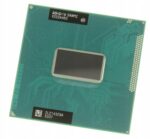 Procesor Intel z widoczną metalową powierzchnią termiczną i siatką złotych pinów na zielonym podłożu PCB.