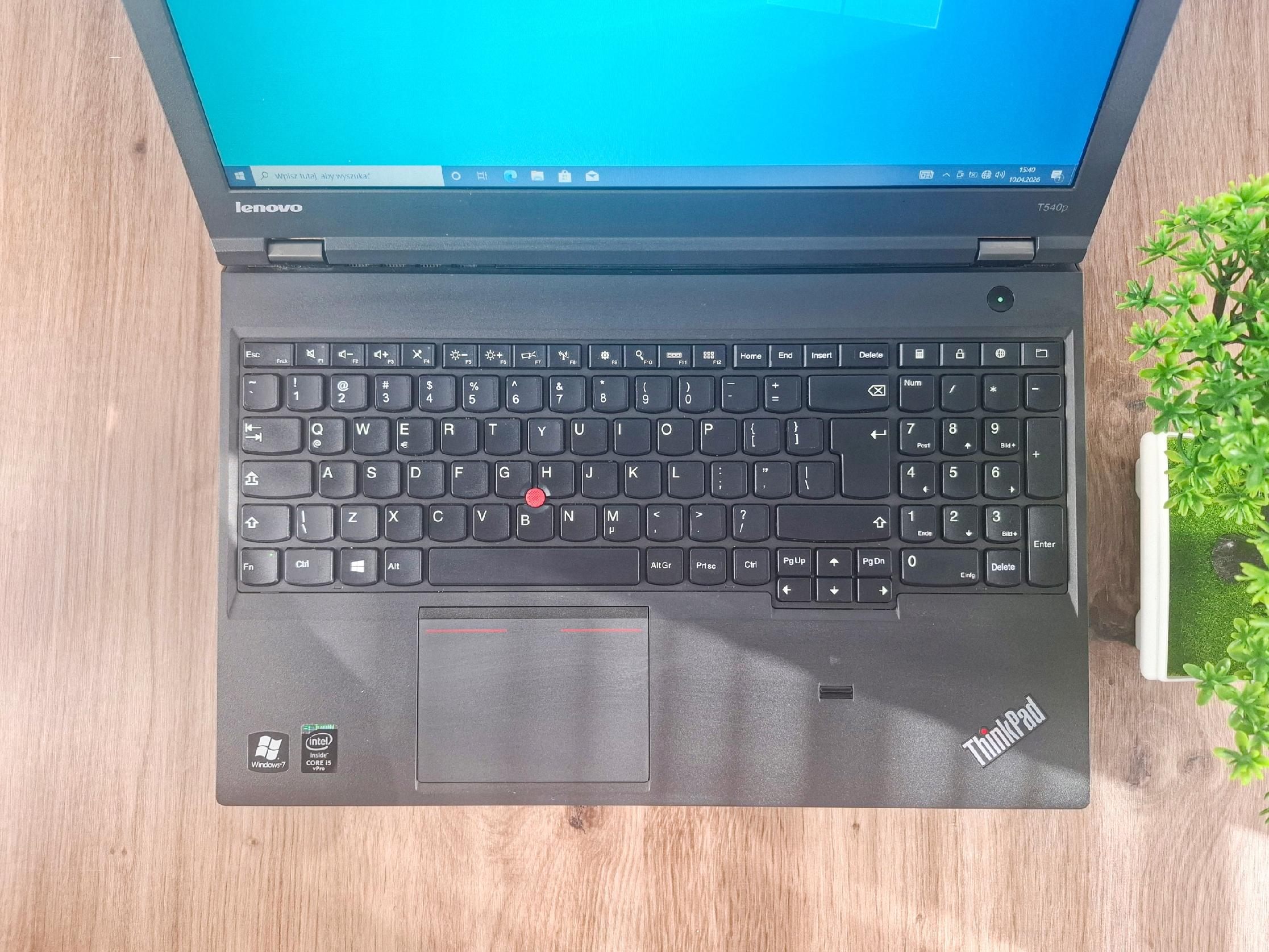 Otwarty laptop Lenovo ThinkPad T540p widziany z góry, ekran włączony niebieskim tłem, klawiatura ze śladami użytkowania.