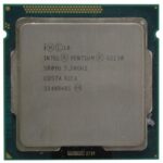 Procesor Intel Pentium G2130 widziany z góry, złote piny na krawędzi, widoczne oznaczenia i naklejka na powierzchni.