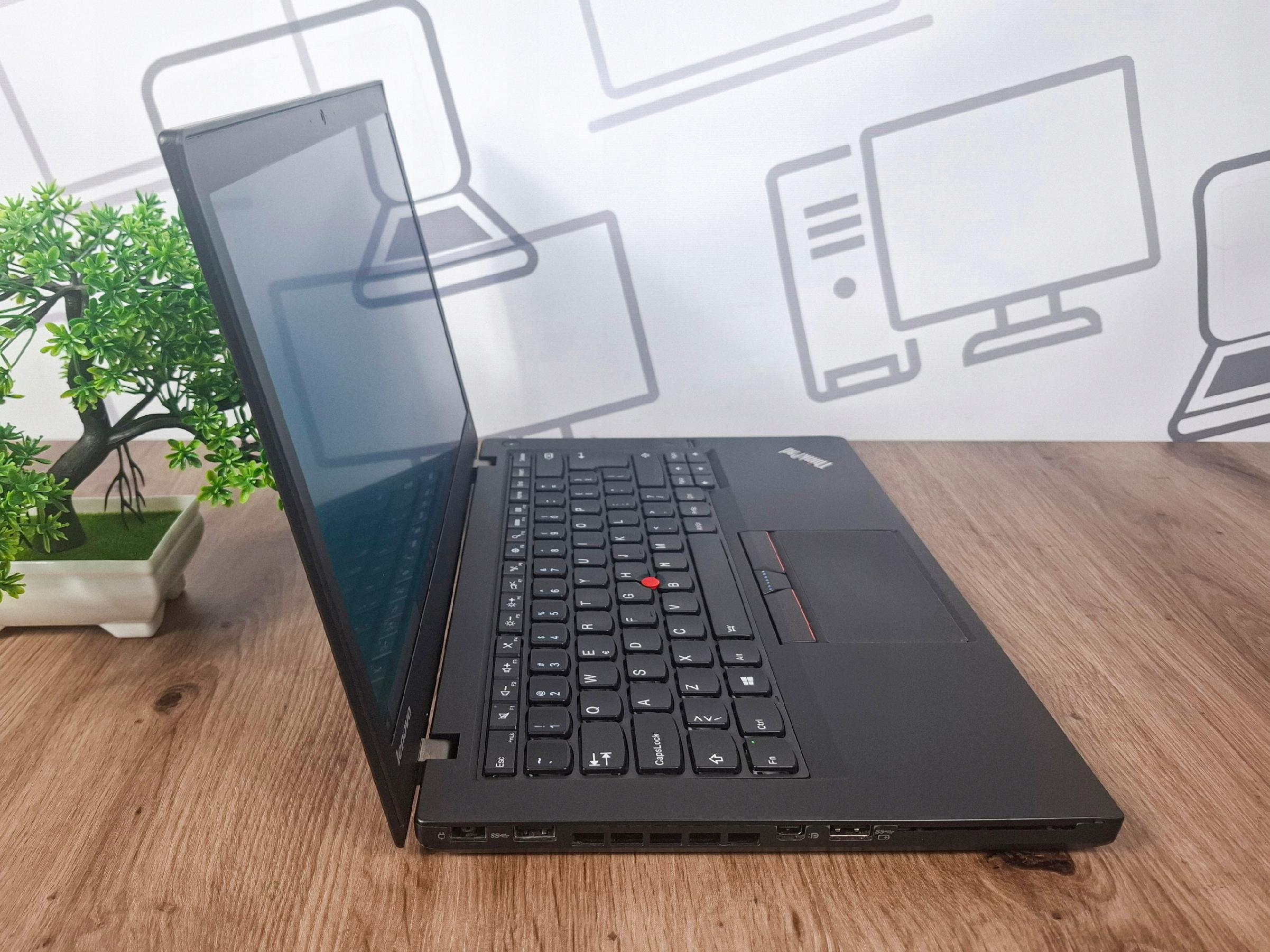 Otwarty laptop Lenovo ThinkPad T450s pod kątem z lewej strony, widoczna klawiatura z czerwonym TrackPointem i wygaszony ekran